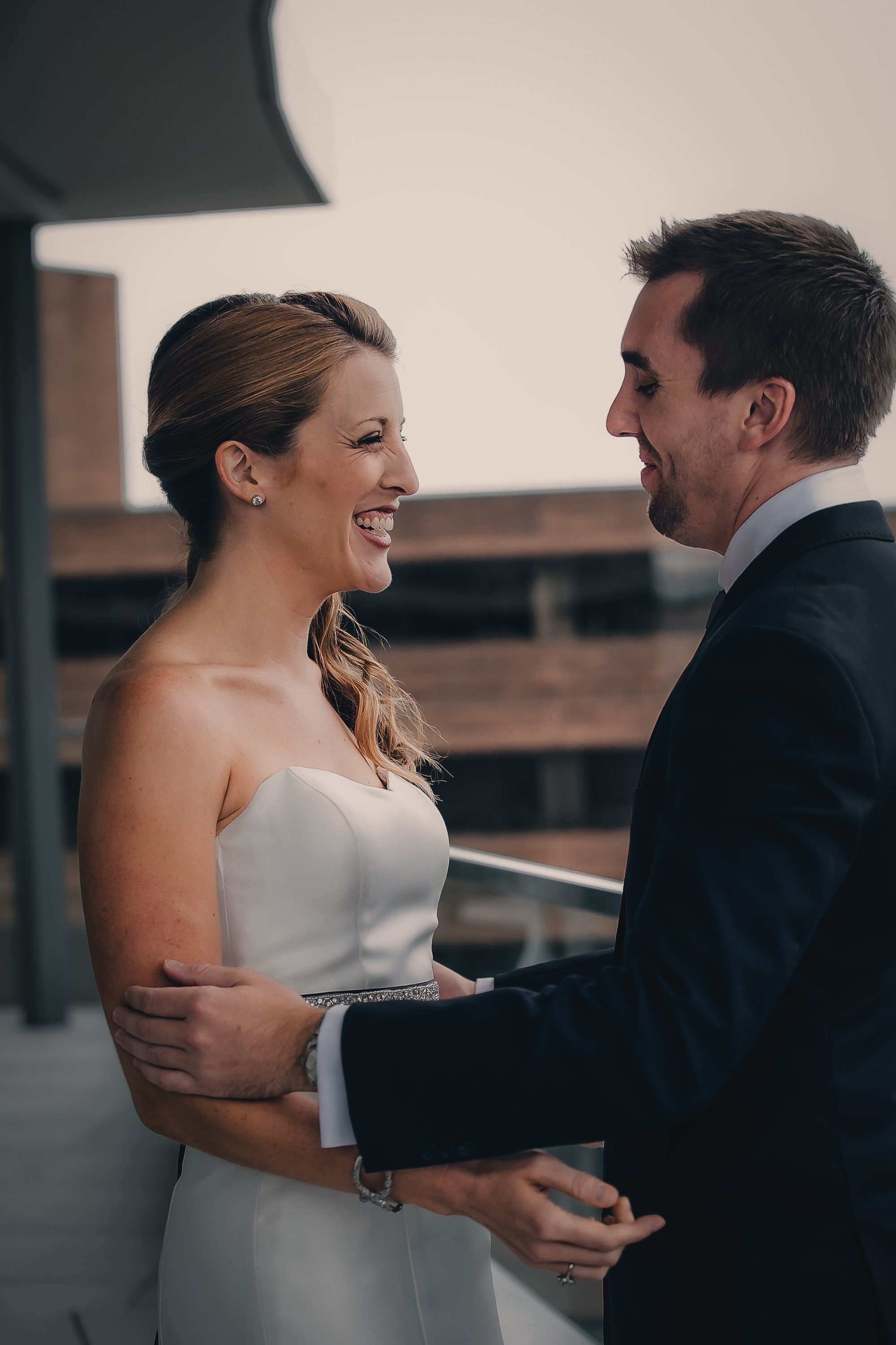 A bride and groom are holding hands and smiling at each other during their wedding ceremony.
