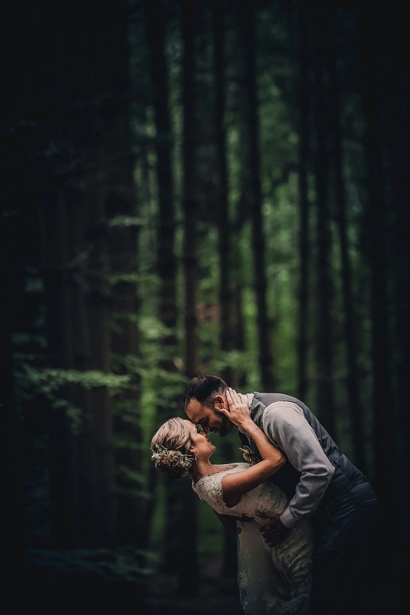 A bride and groom sharing a romantic dance in a forest, with the groom dipping the bride as they gaze into each other's eyes.