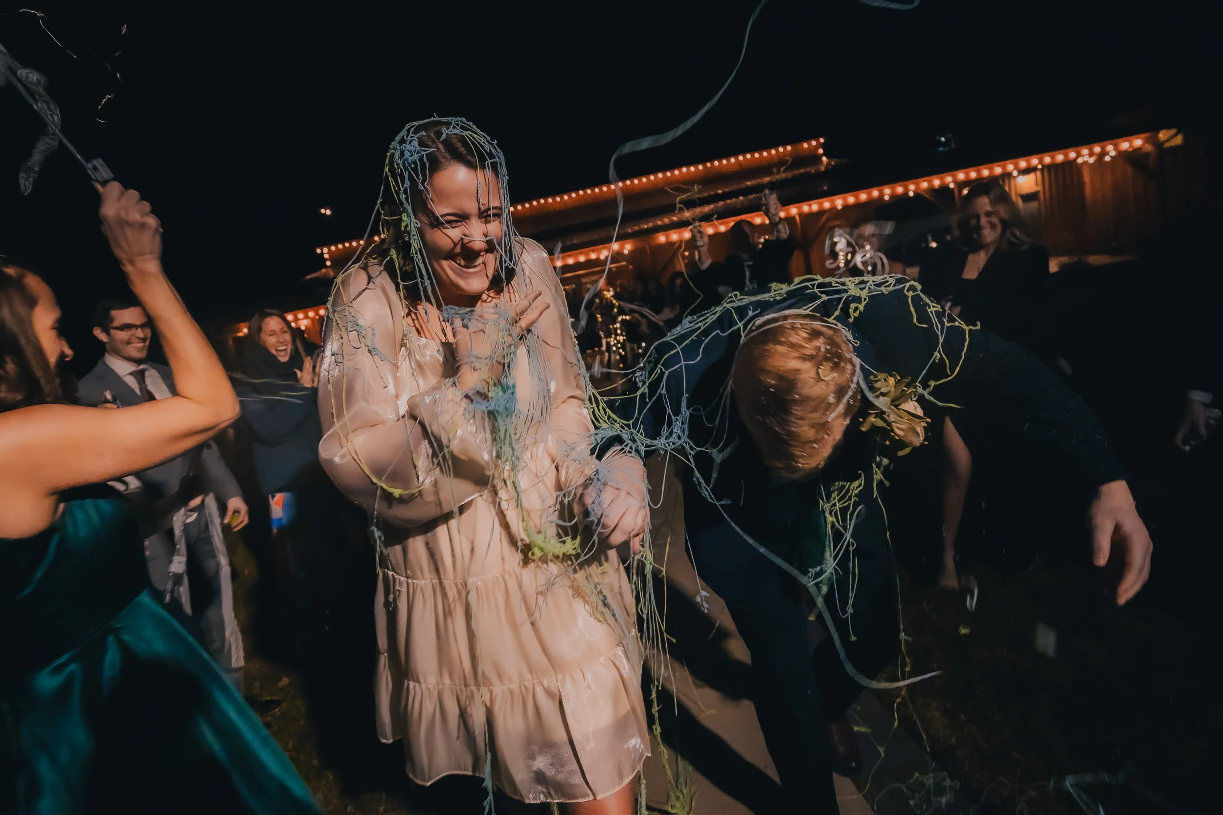 People celebrating at a party with colorful streamers and confetti, smiling, and enjoying the event.