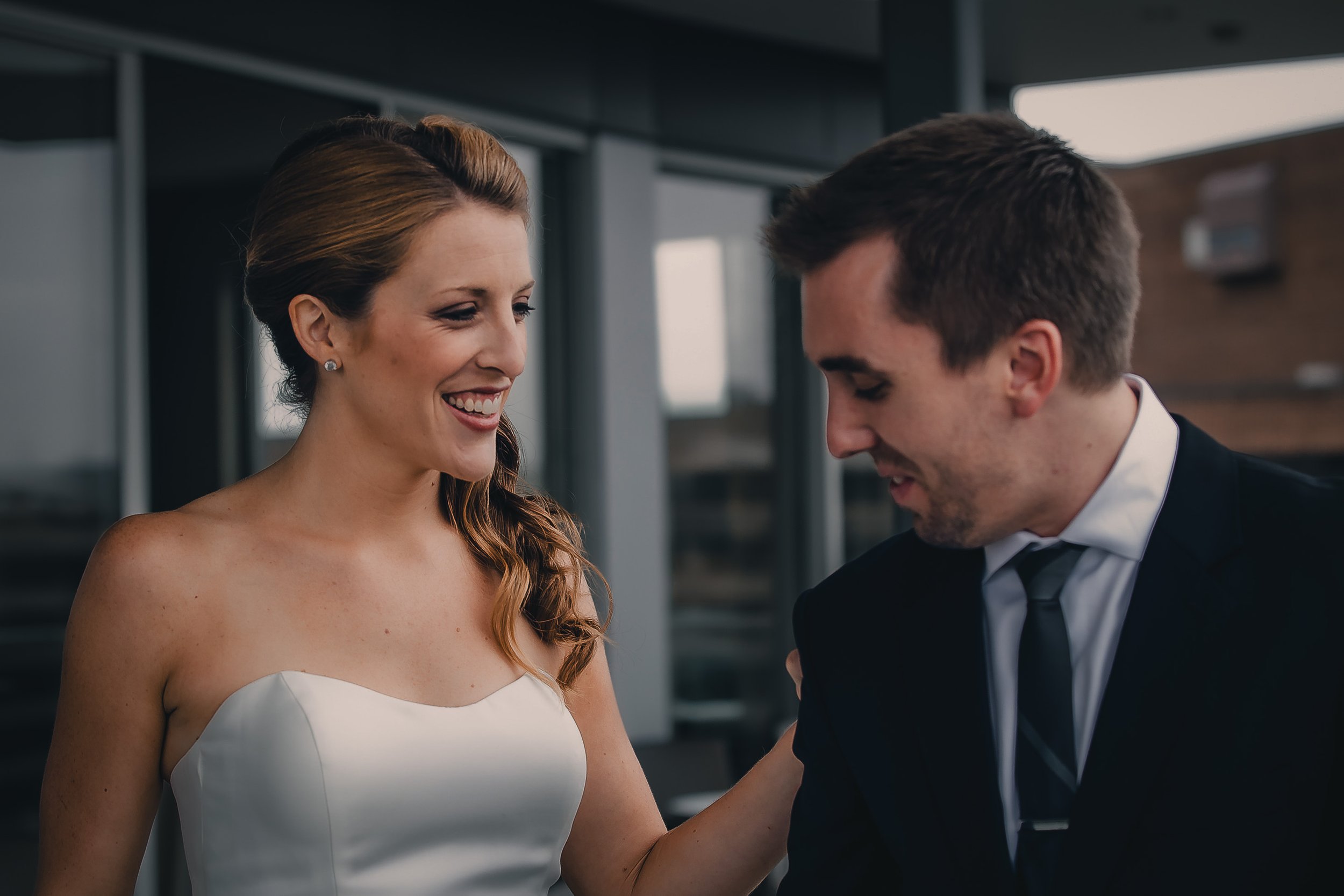 A smiling woman in a wedding dress interacts with a man in a suit during a wedding celebration.