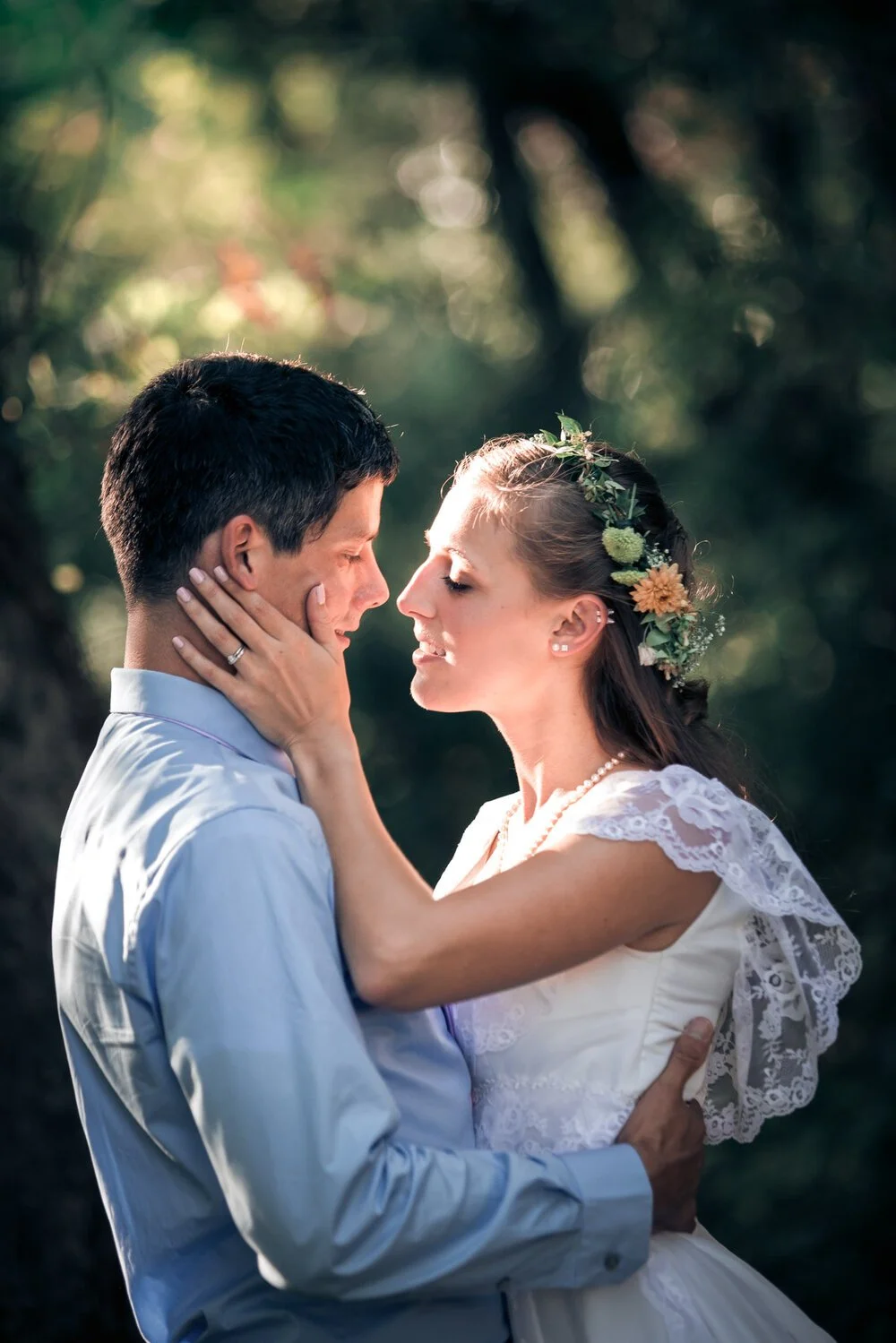 A bride with her hand on the grooms face as they are about to kiss.