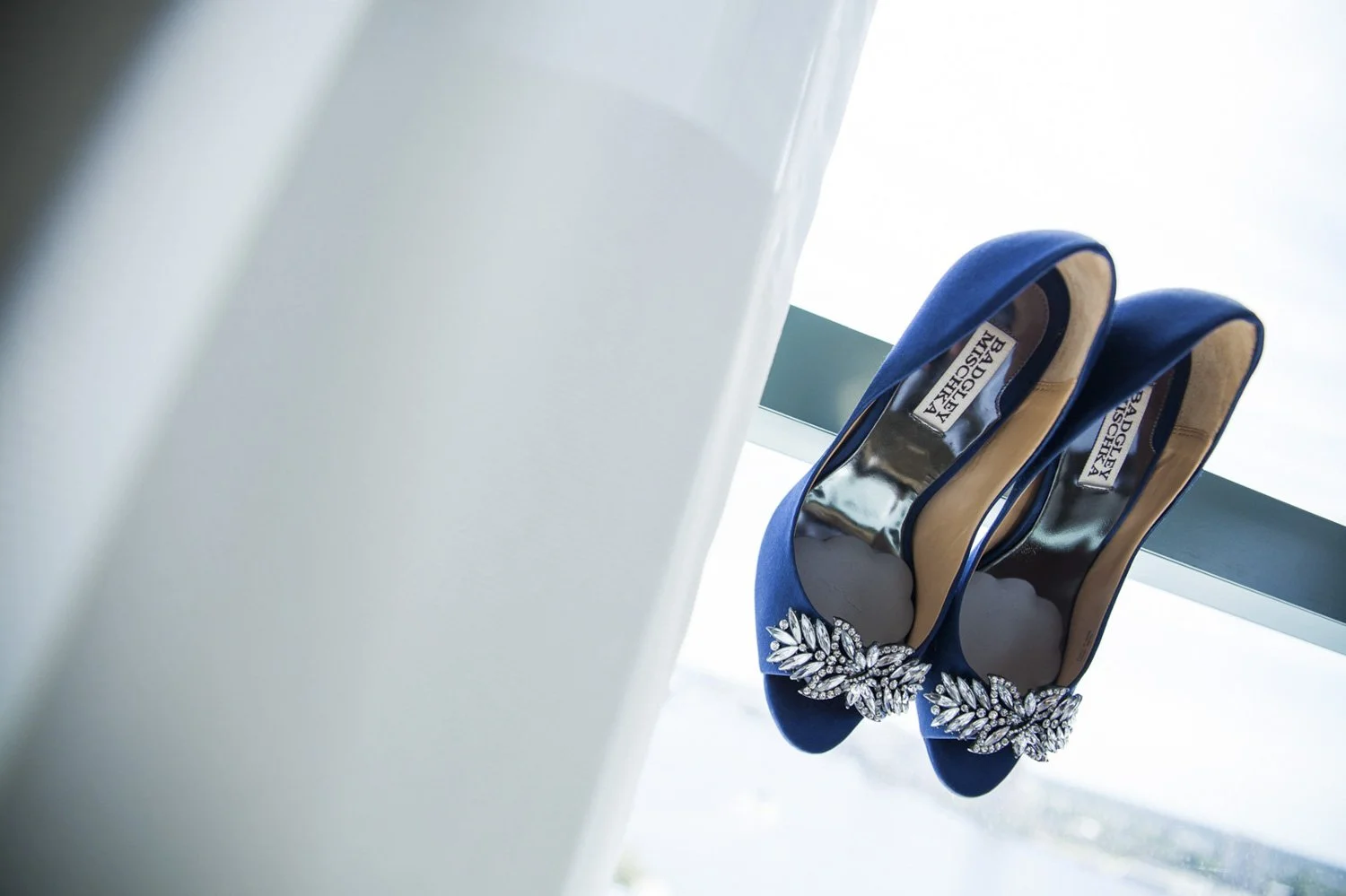 A bride's blue high heels posed on a window.