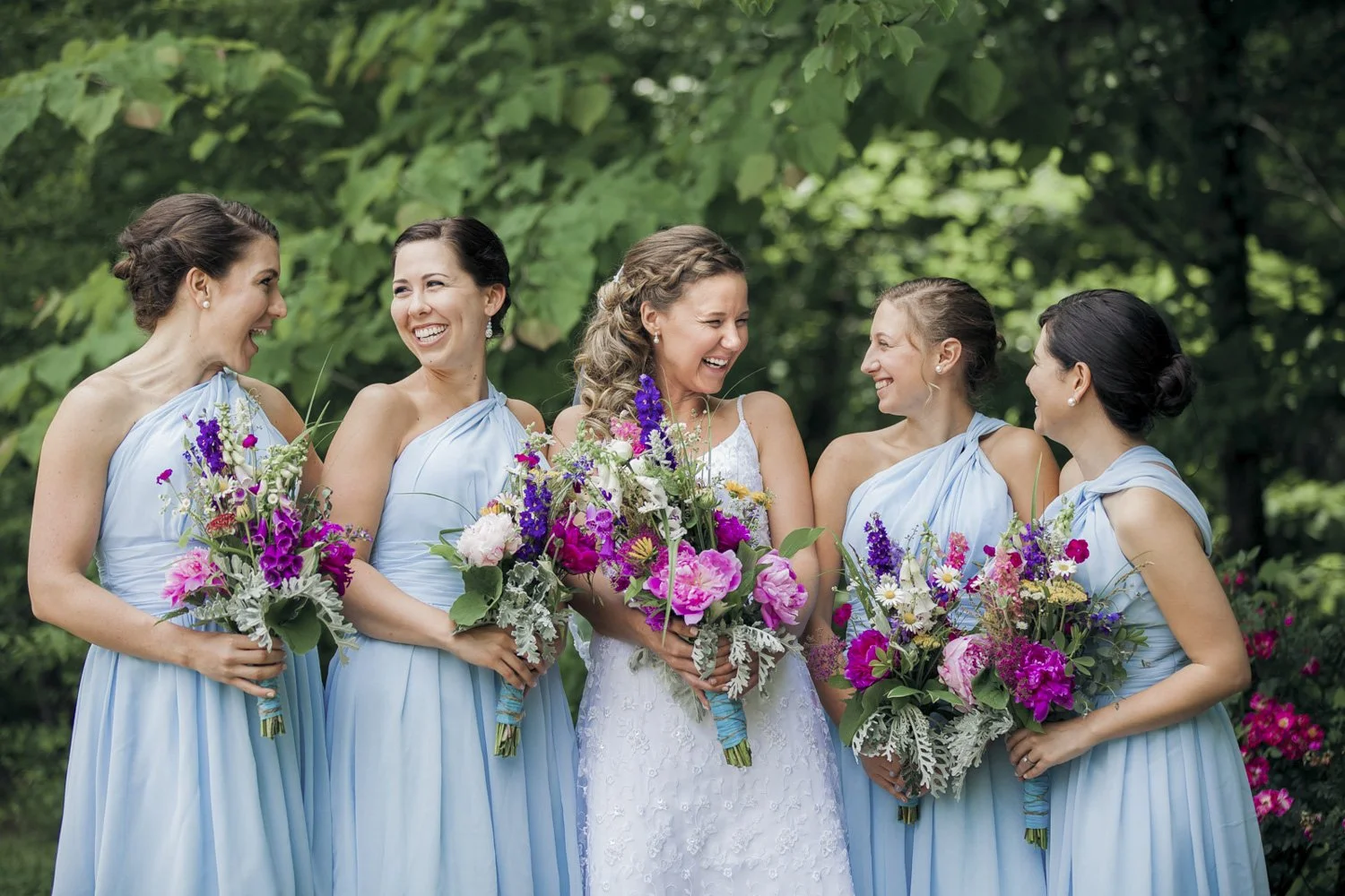 A bride having a laugh with her four bridesmaids while holding their bouquets