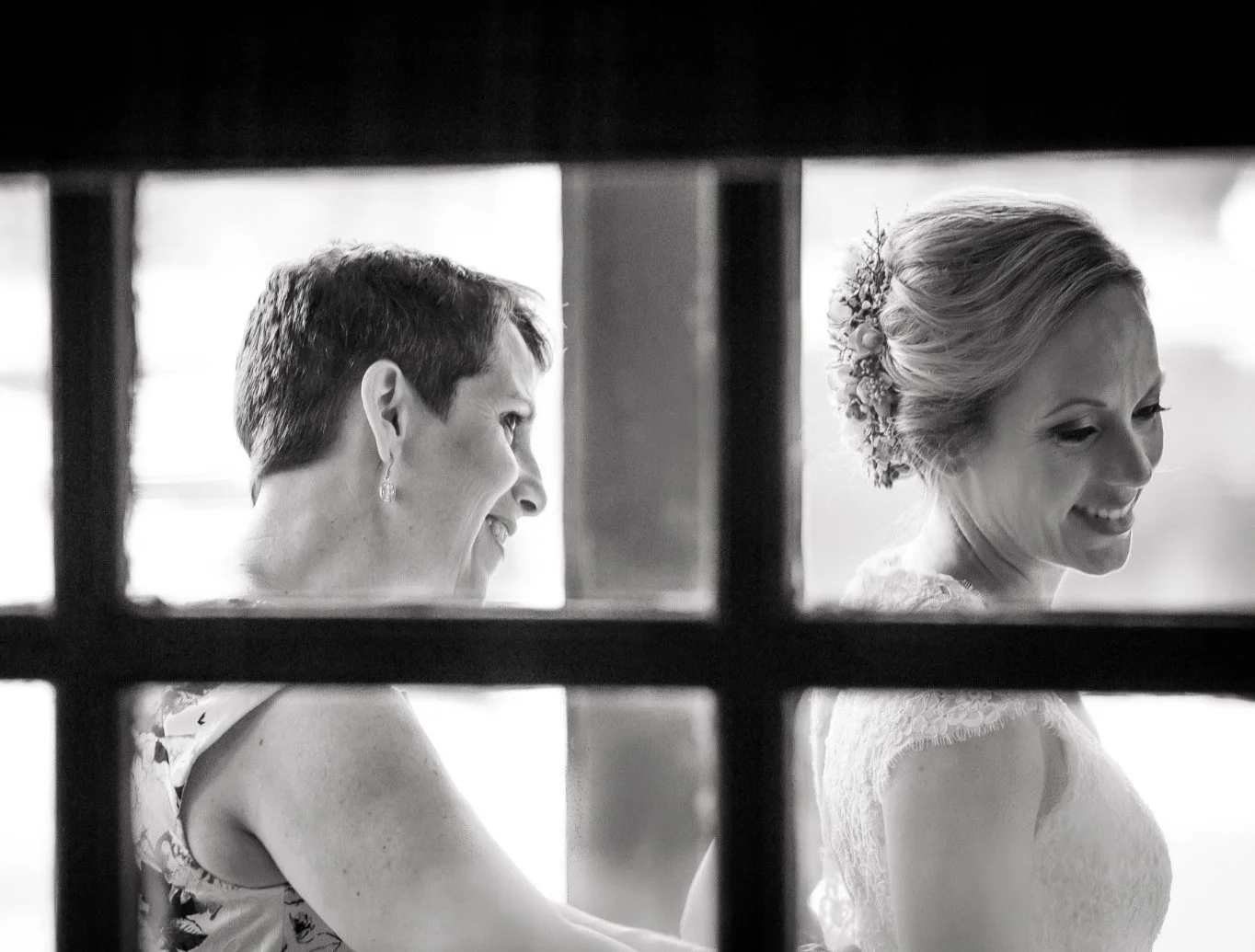 A bride's mother helping her put on her wedding dress.