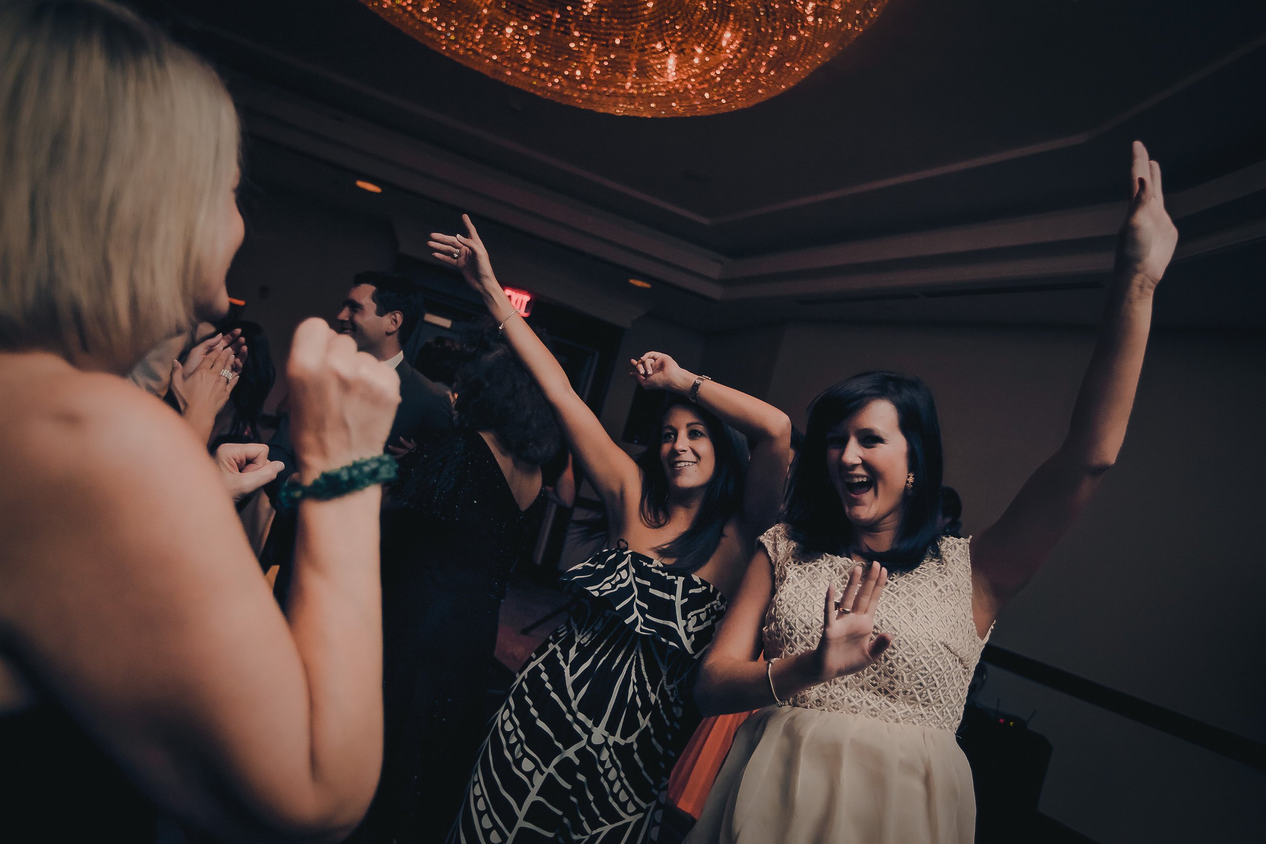 Group of women dancing and having fun at a party or celebration in a dimly lit room.