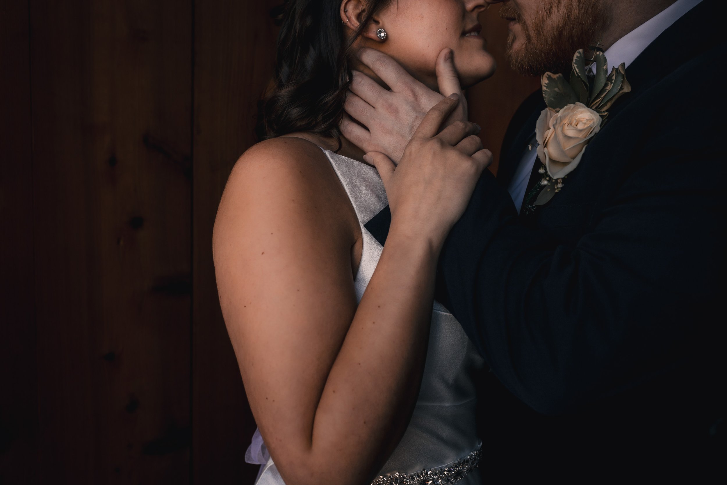 A close-up of a couple in formal attire, sharing an intimate moment, with the woman touching the man's face and neck.