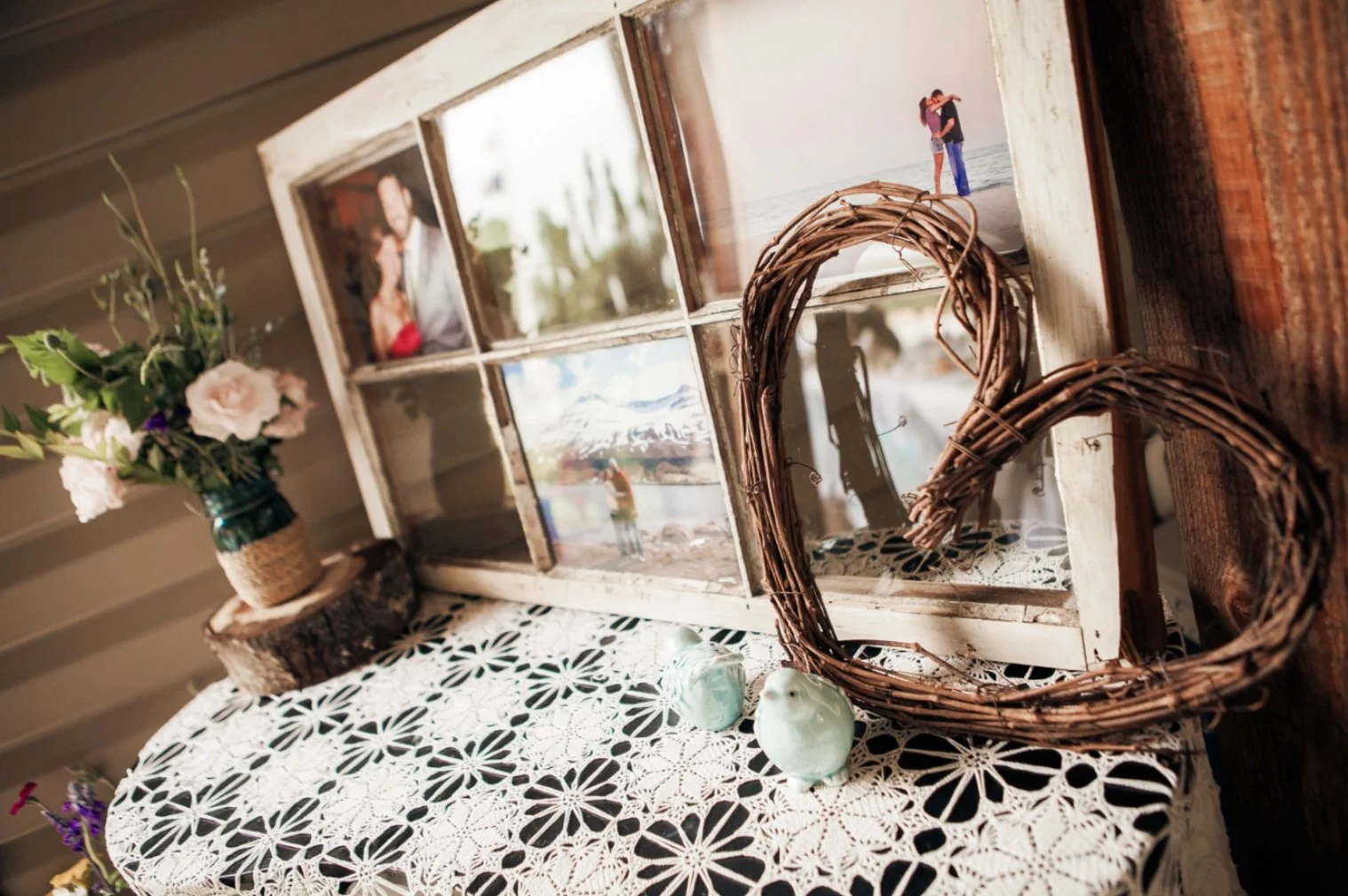 A close up of a heart-shaped prop made of twigs against a collage of engagement photos.