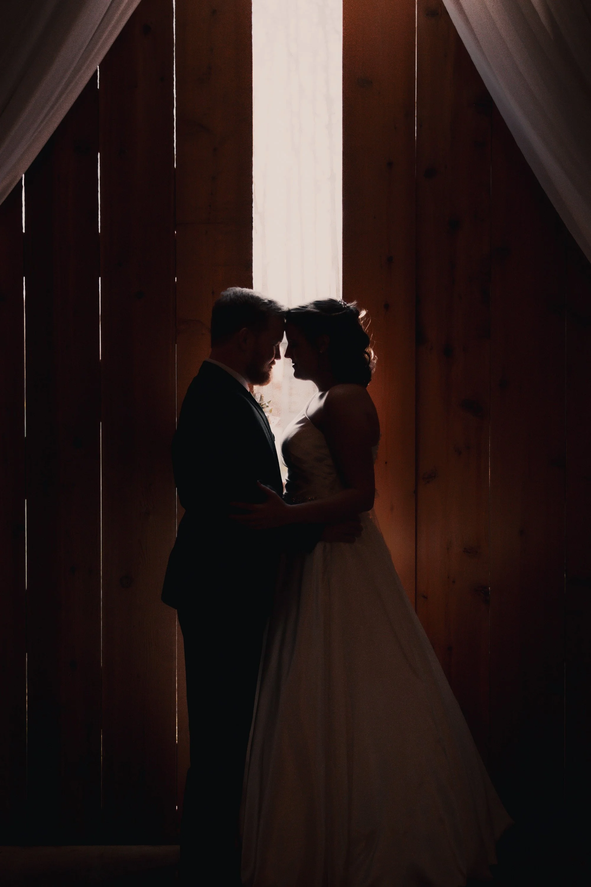 Silhoutte of couple by slightly open barn doors.