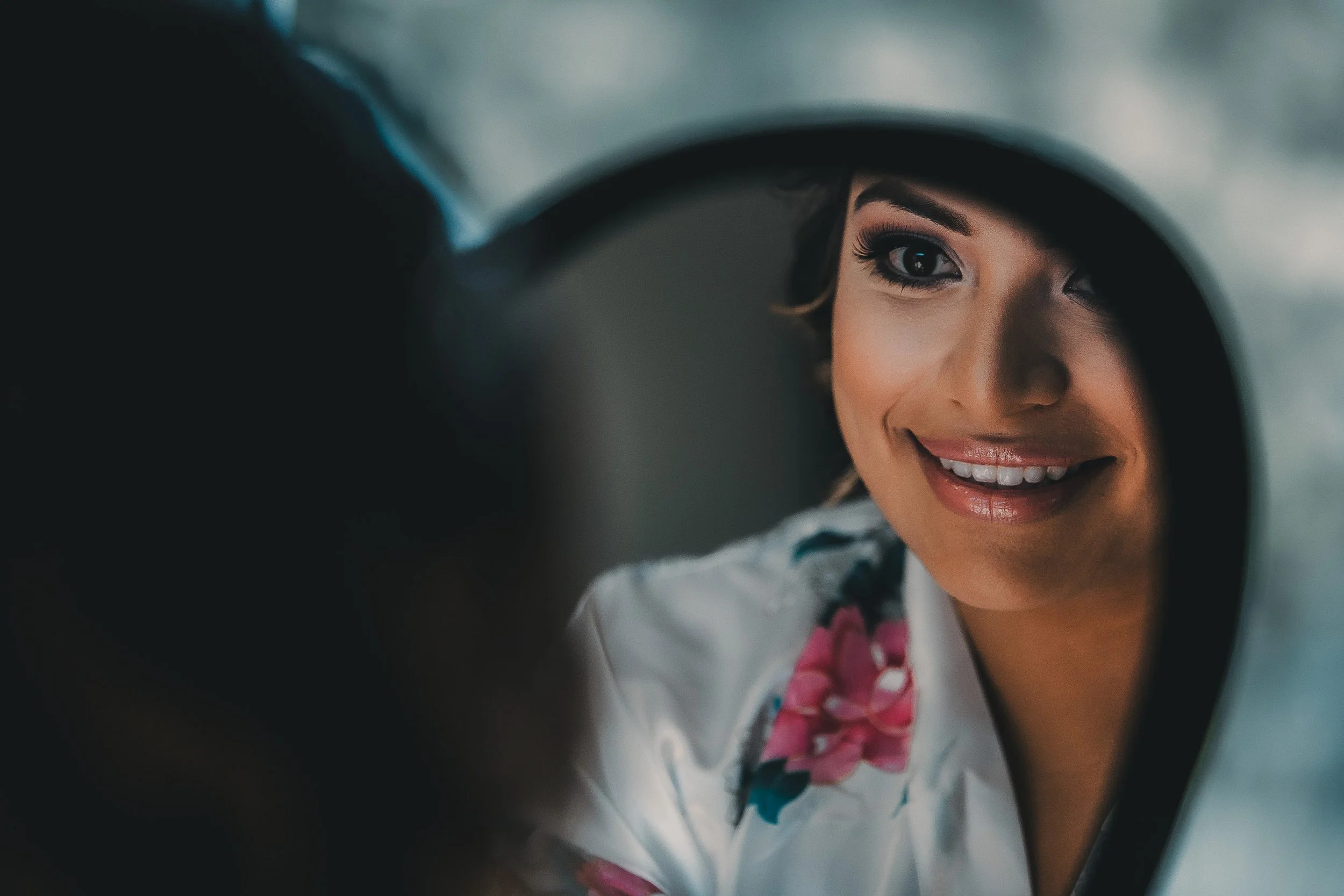 A woman smiling as she looks at her reflection in a mirror.