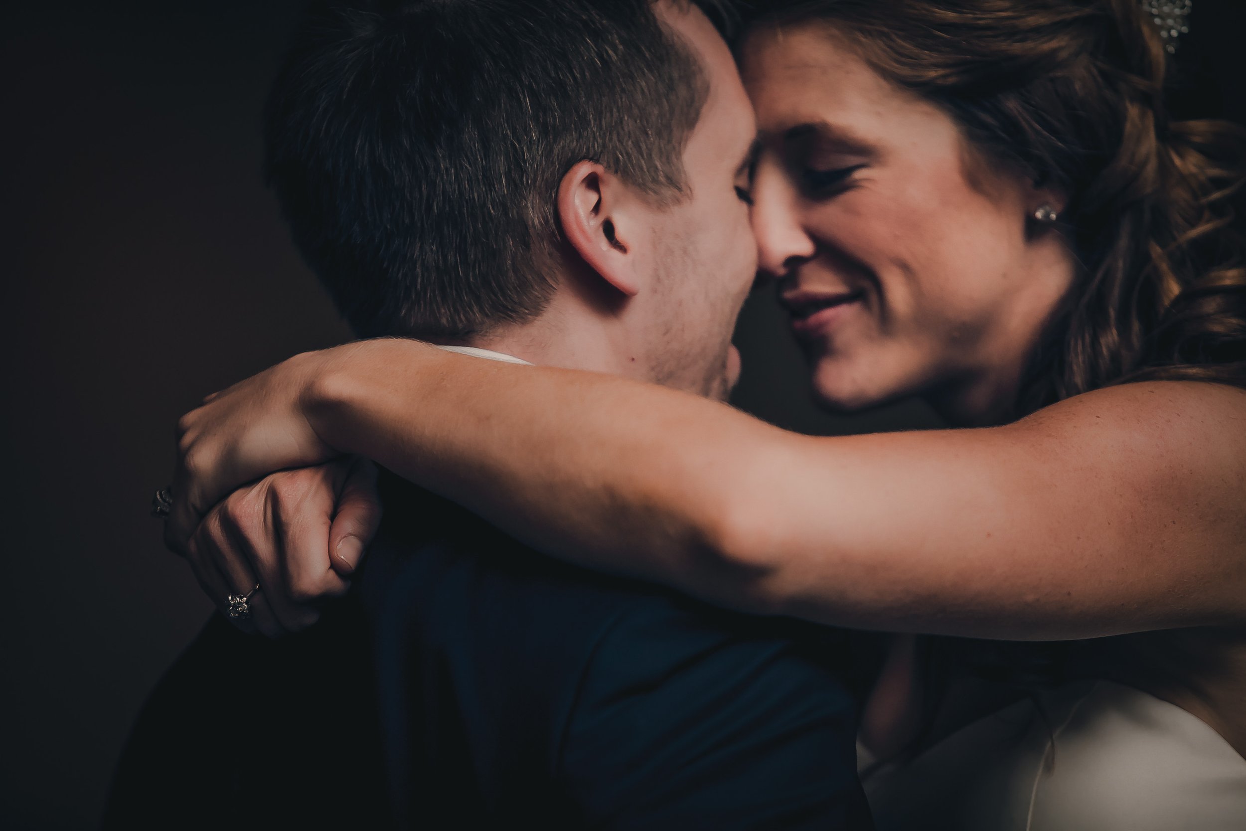 A close-up of a young couple embracing, with their faces touching and eyes closed, appearing happy and romantic.