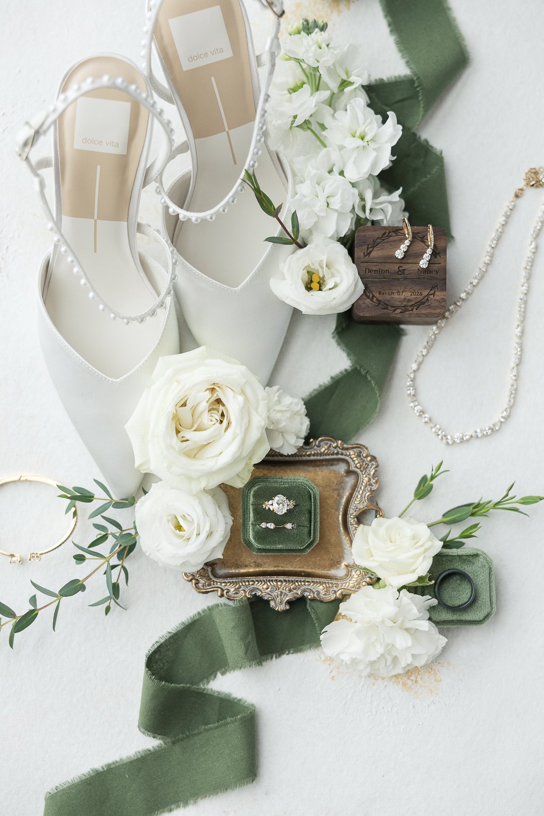 Wedding detail flat lay featuring rings, heirloom jewelry, and bridal accessories