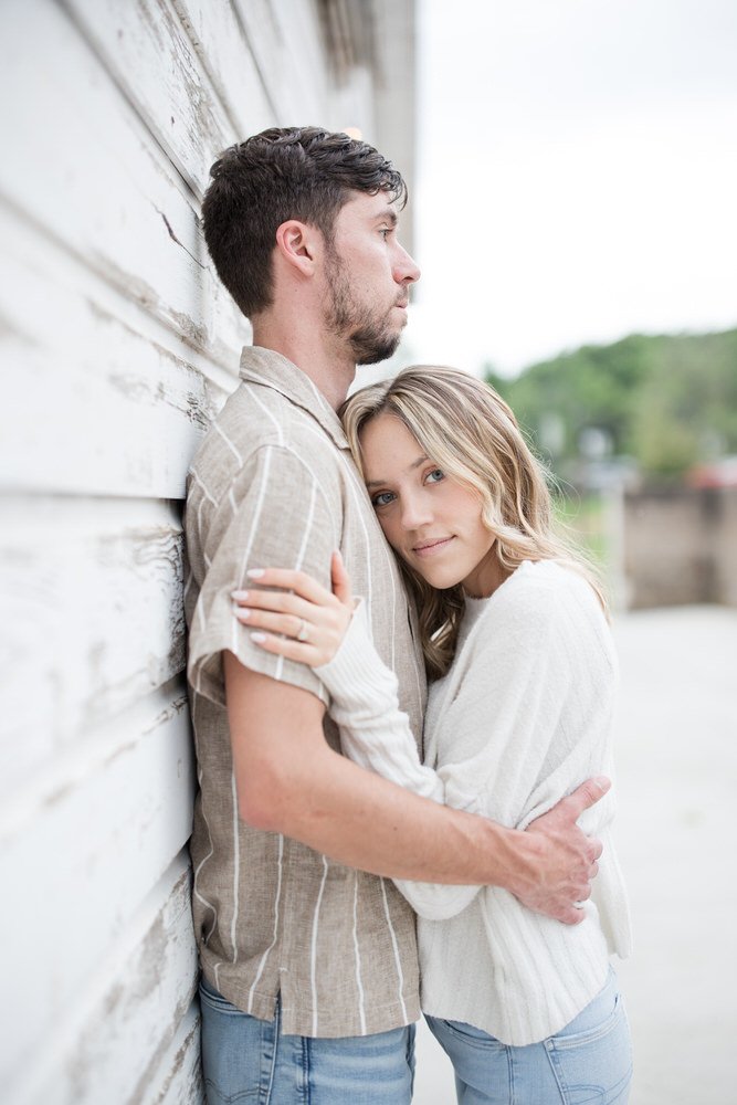 Couple embracing against a weathered wooden wall