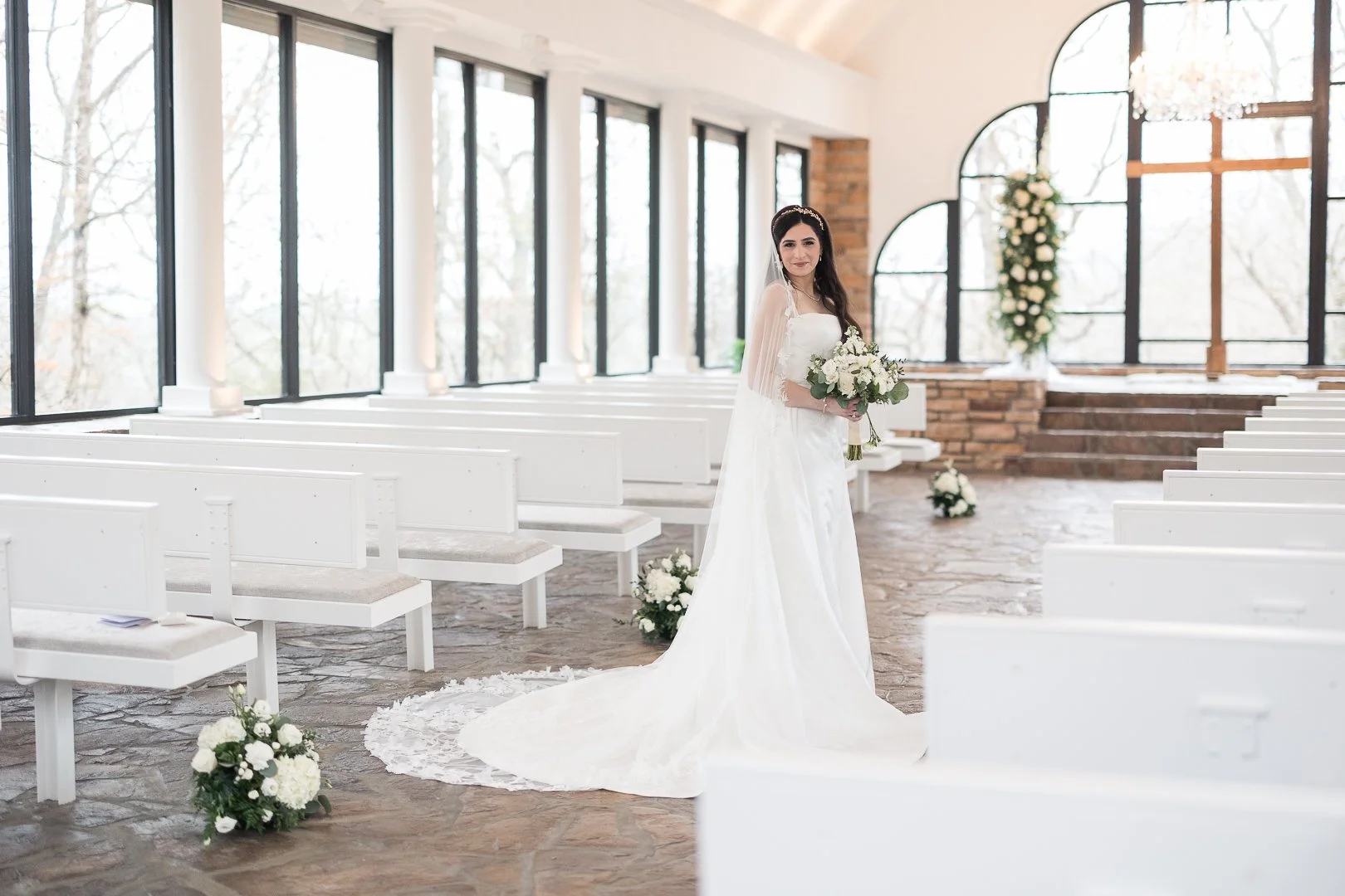 Bride standing inside a glass chapel during wedding portraits in Branson Missouri