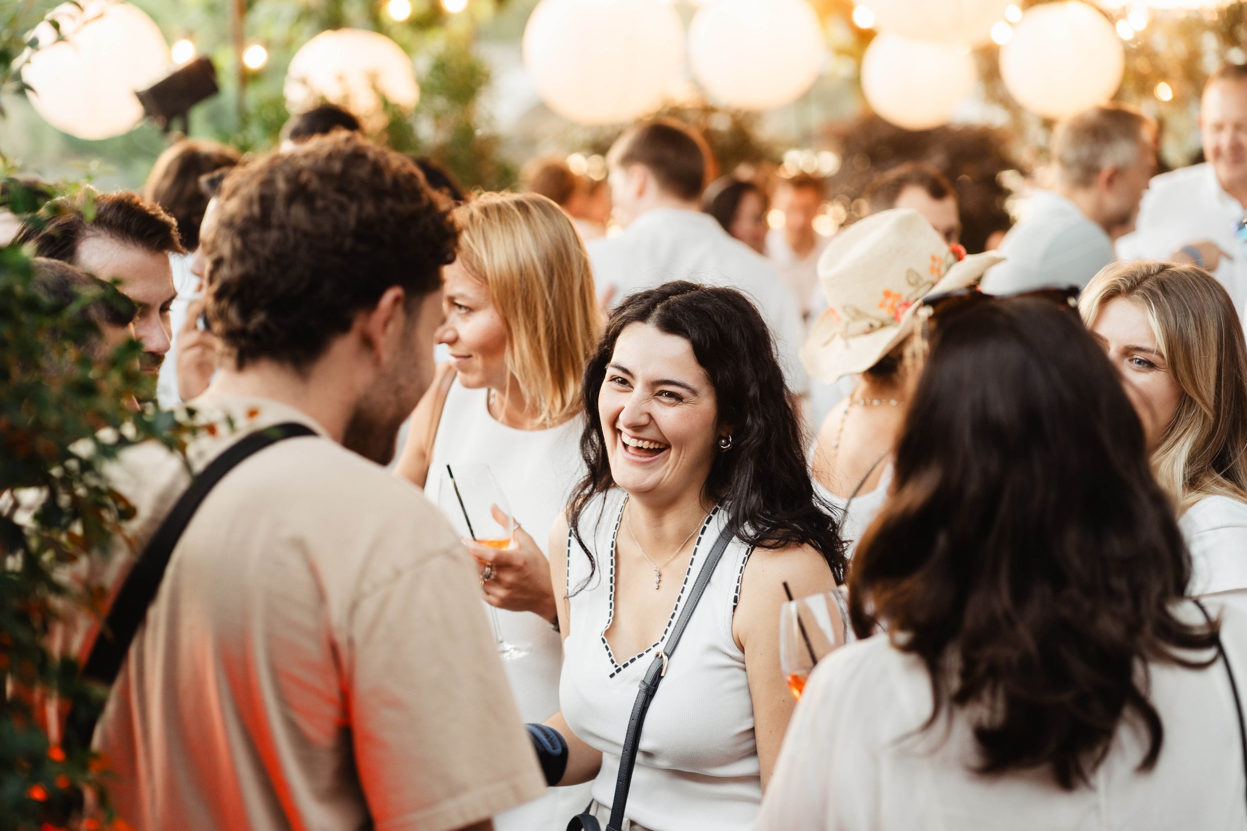 People socializing at an outdoor gathering with warm lighting and lanterns