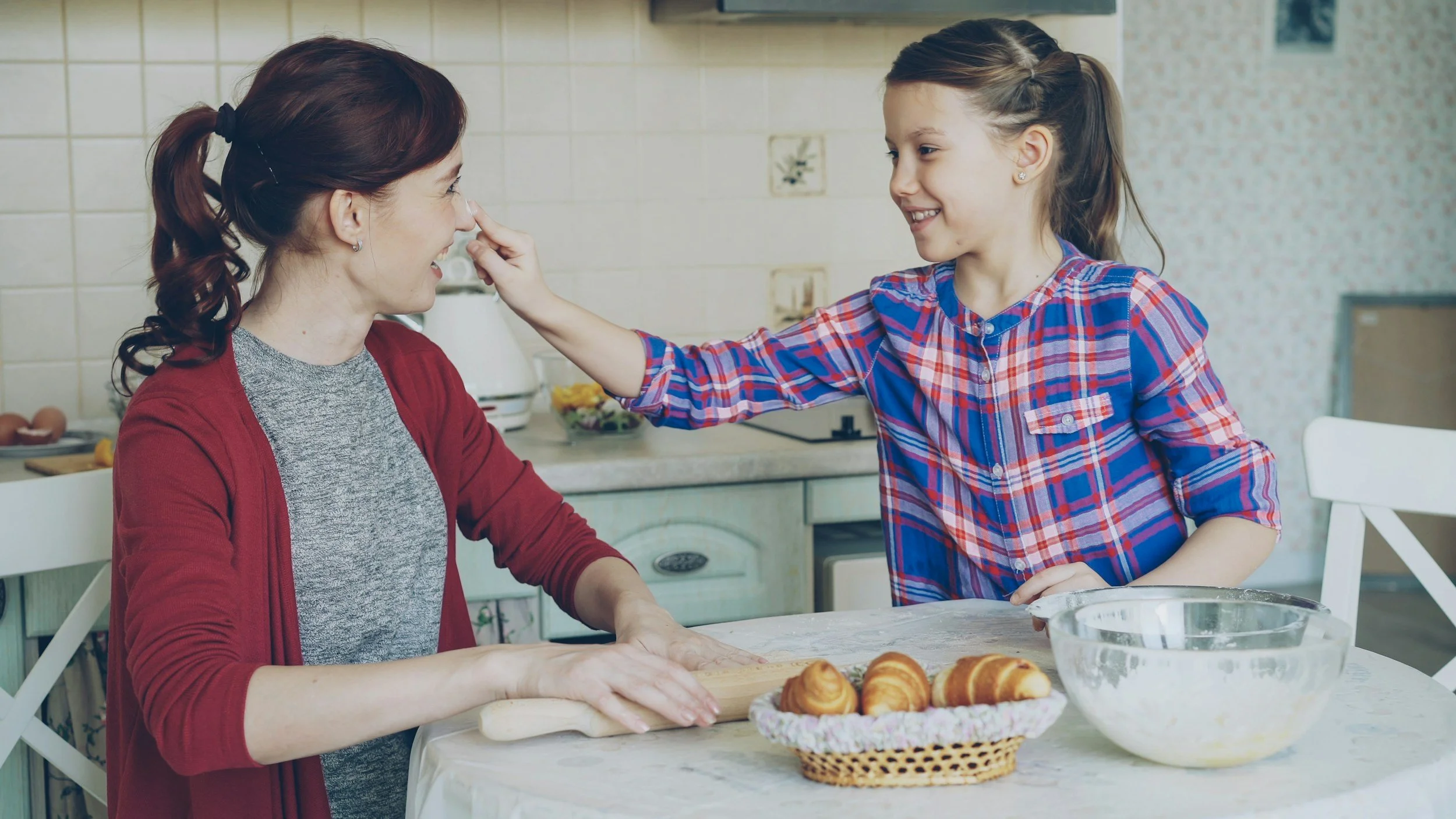 A girl touching a woman's nose in a kitchen