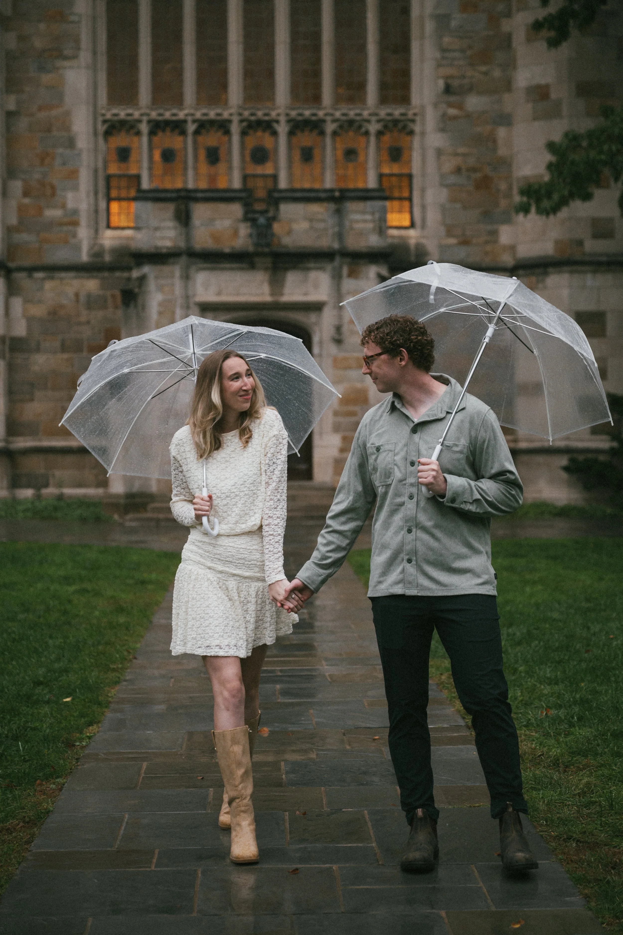 mand and woman holding hands in the rain under clear umbrellas in front of a church