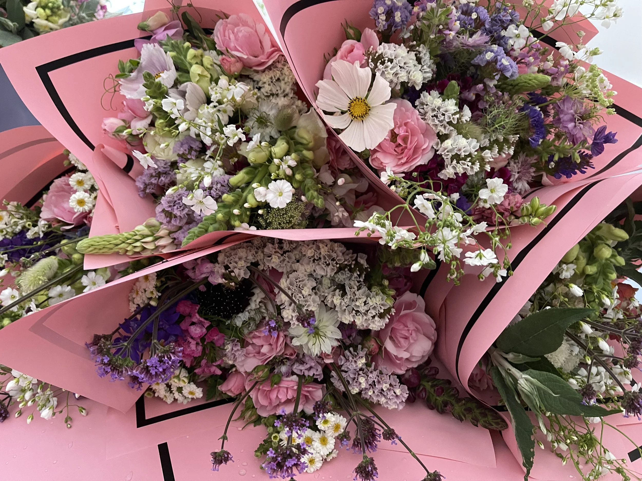 Bouquets of mixed flowers wrapped in pink paper.