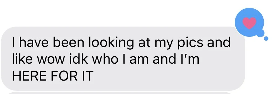 A screenshot of a text message with a gray bubble containing the message: "I have been looking at my pics and like wow idk who I am and I'm HERE FOR IT." There is a blue speech bubble with a pink heart icon in the top right corner.