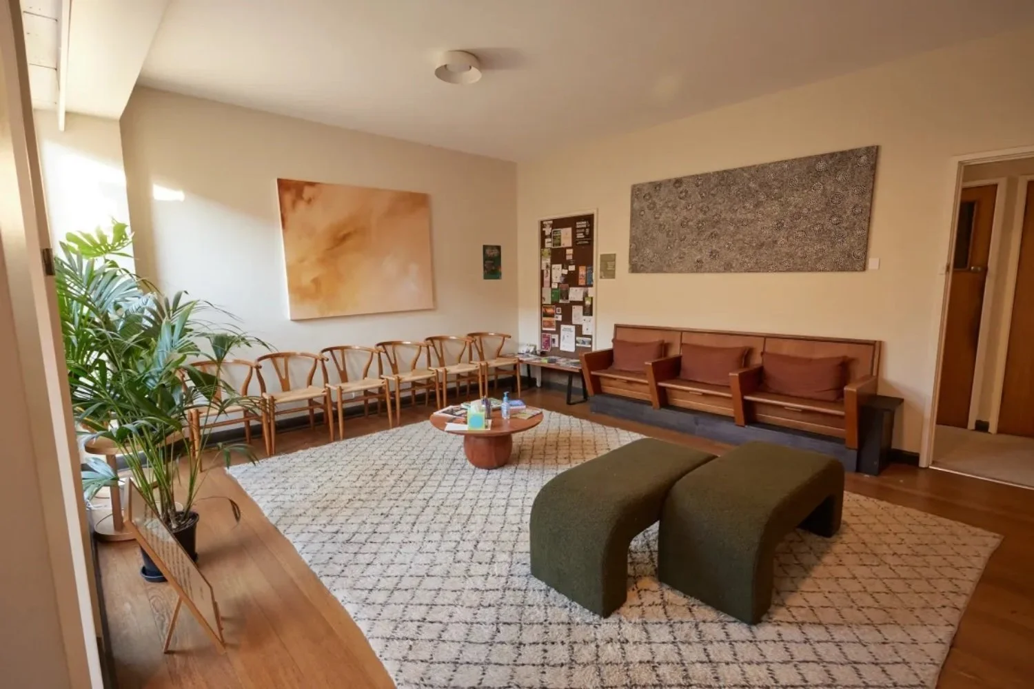 The waiting room: timber chairs, plants and a soft rug in warm afternoon light
