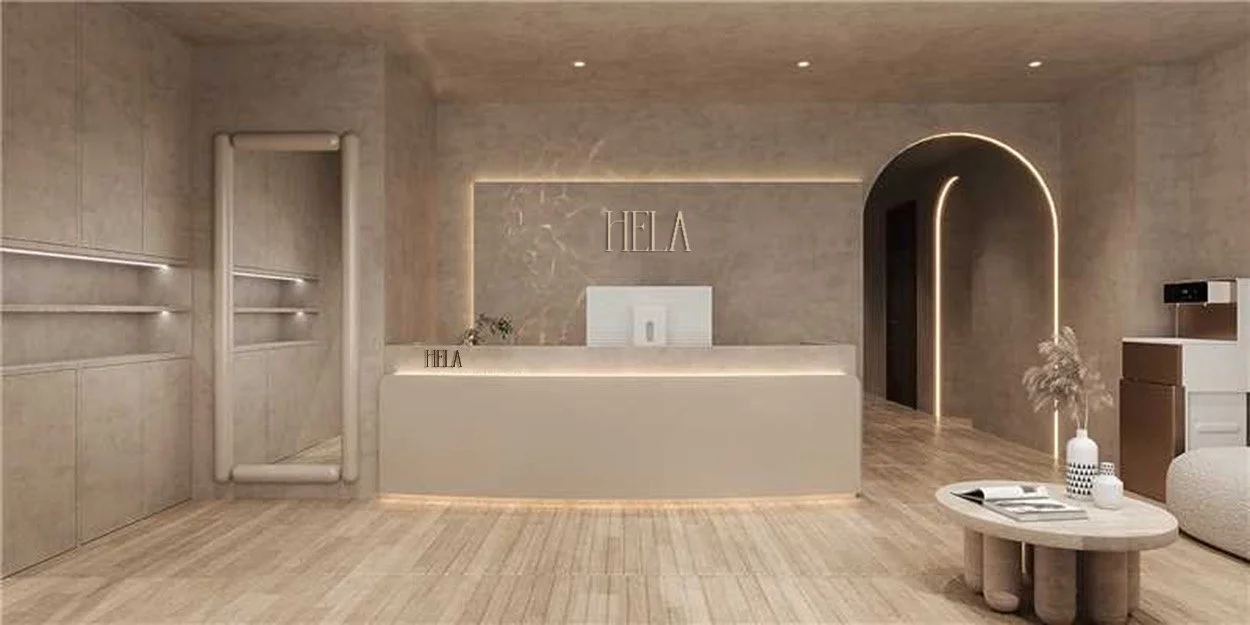 Modern reception area with a neutral beige color scheme, featuring a minimalist front desk, decorative plants, and wall art that spells 'HELA'. There is a small round table with vases, a seating area, and an archway with LED lighting leading to another room.