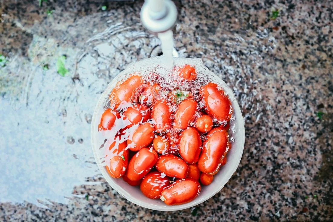 a bowl of tomatoes under running water