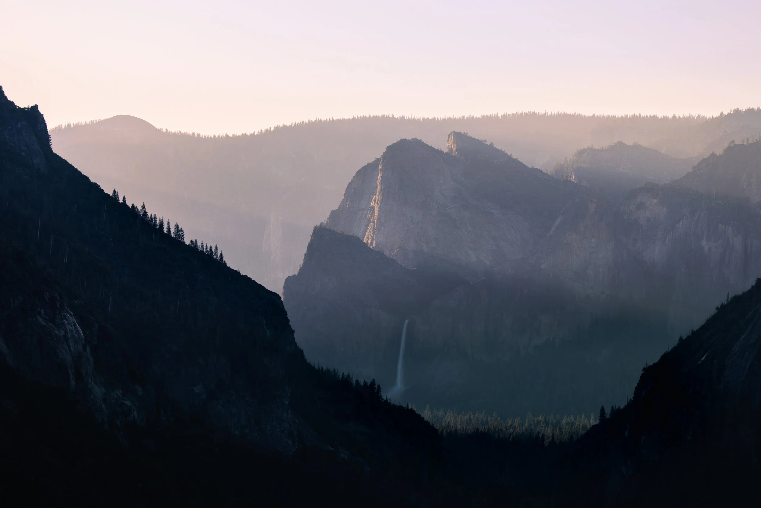 Sunset over a rugged mountain landscape with a waterfall in a valley