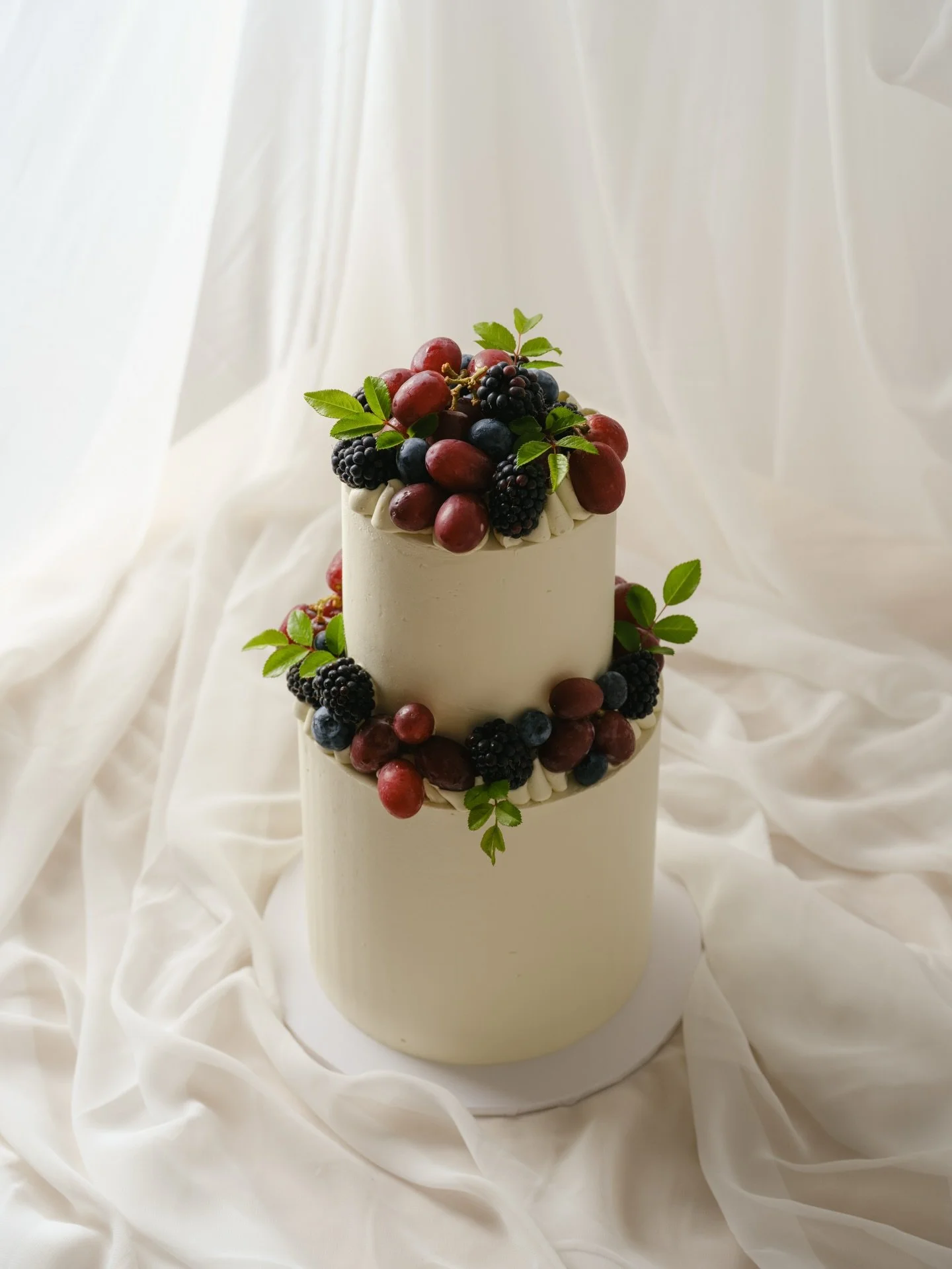 Two tiers of clean white, dark berries, grapes and a touch of foliage to celebrate Emma&rsquo;s milestone birthday (and submitted PhD thesis!!) 🍇🫐🌿

This is our mini two tier with our Berry Rosie flavour done gluten free ✨

#sydneycakes #cakedesig