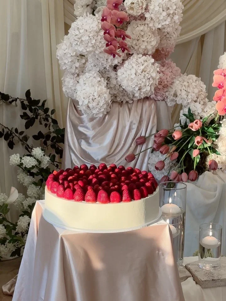 A super clean, ultra minimalist strawberry-topped wedding cake for Janet and Antony. 

Smooth sides and sharp edges all around for a beautiful contrast with all the draped fabric and cascading florals by @filmicbypeony 🥀

Our cake in golden hour ☀️
