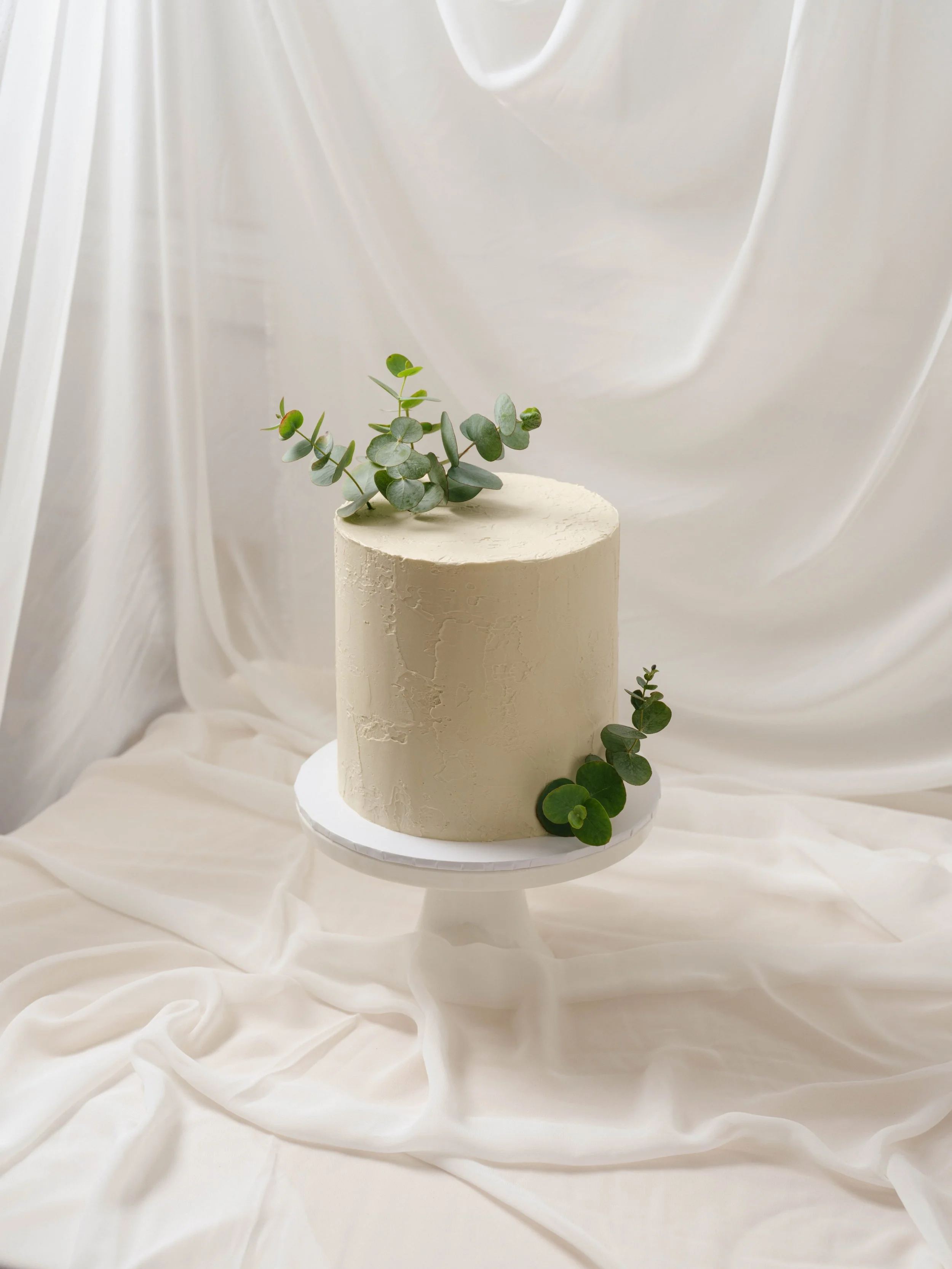 Soft, stucco style textures in a warm ivory plus native foliage on this minimalist birthday cake 🌿

Original design by @stacybrewercakes