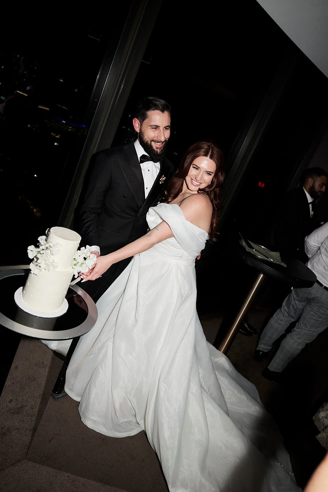 Couple cutting two tier wedding cake with flowers and delicate dotted pearl design - photo by Mandy Wood