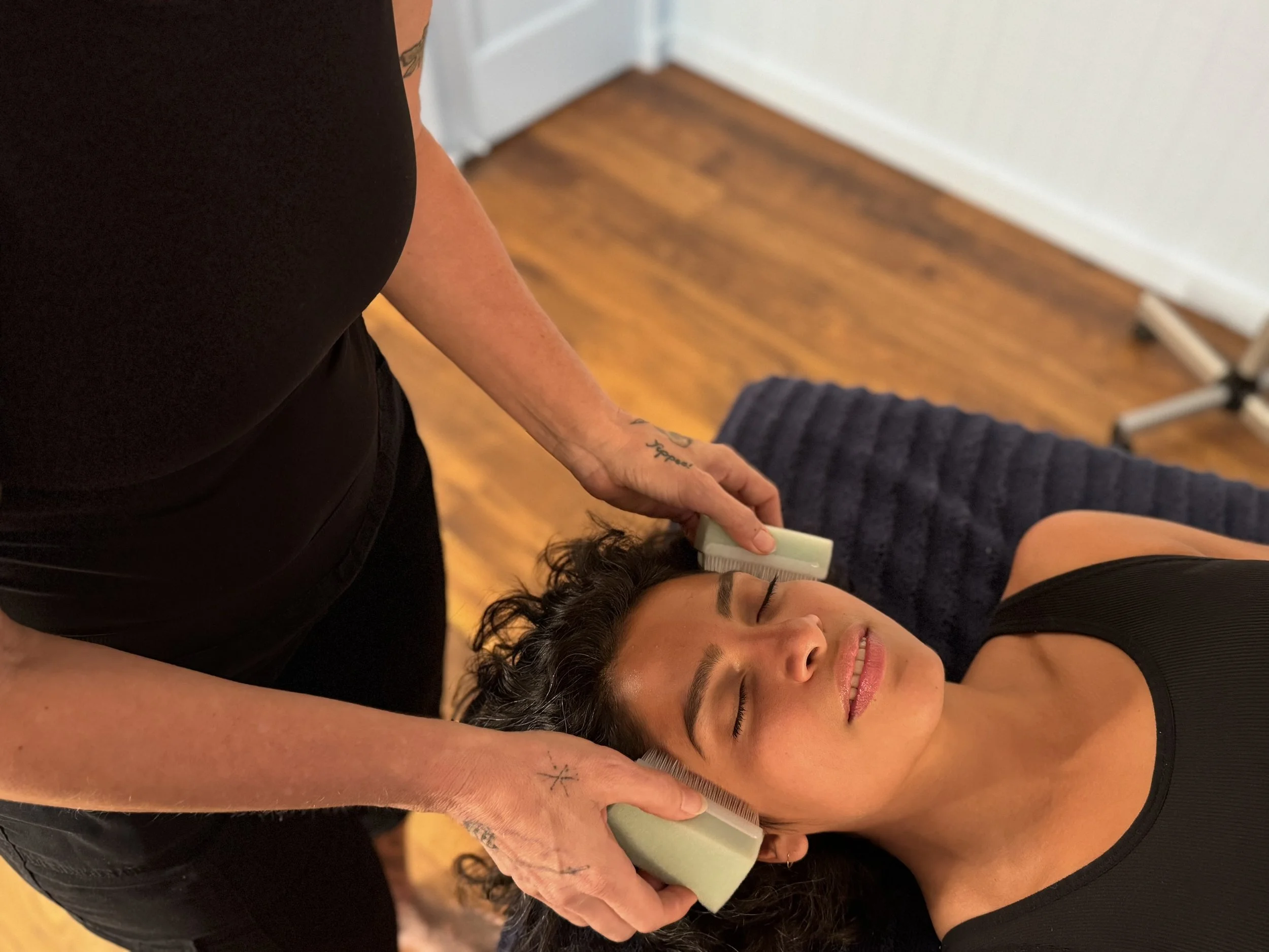 A woman receiving gentle face and head scratches with soft baby brushes