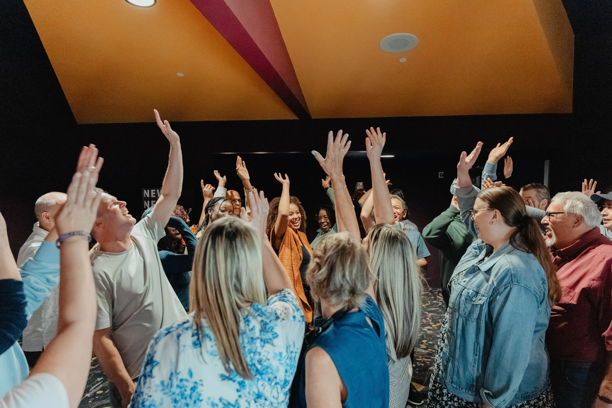 Crowd of people cheering with raised hands at an indoor event
