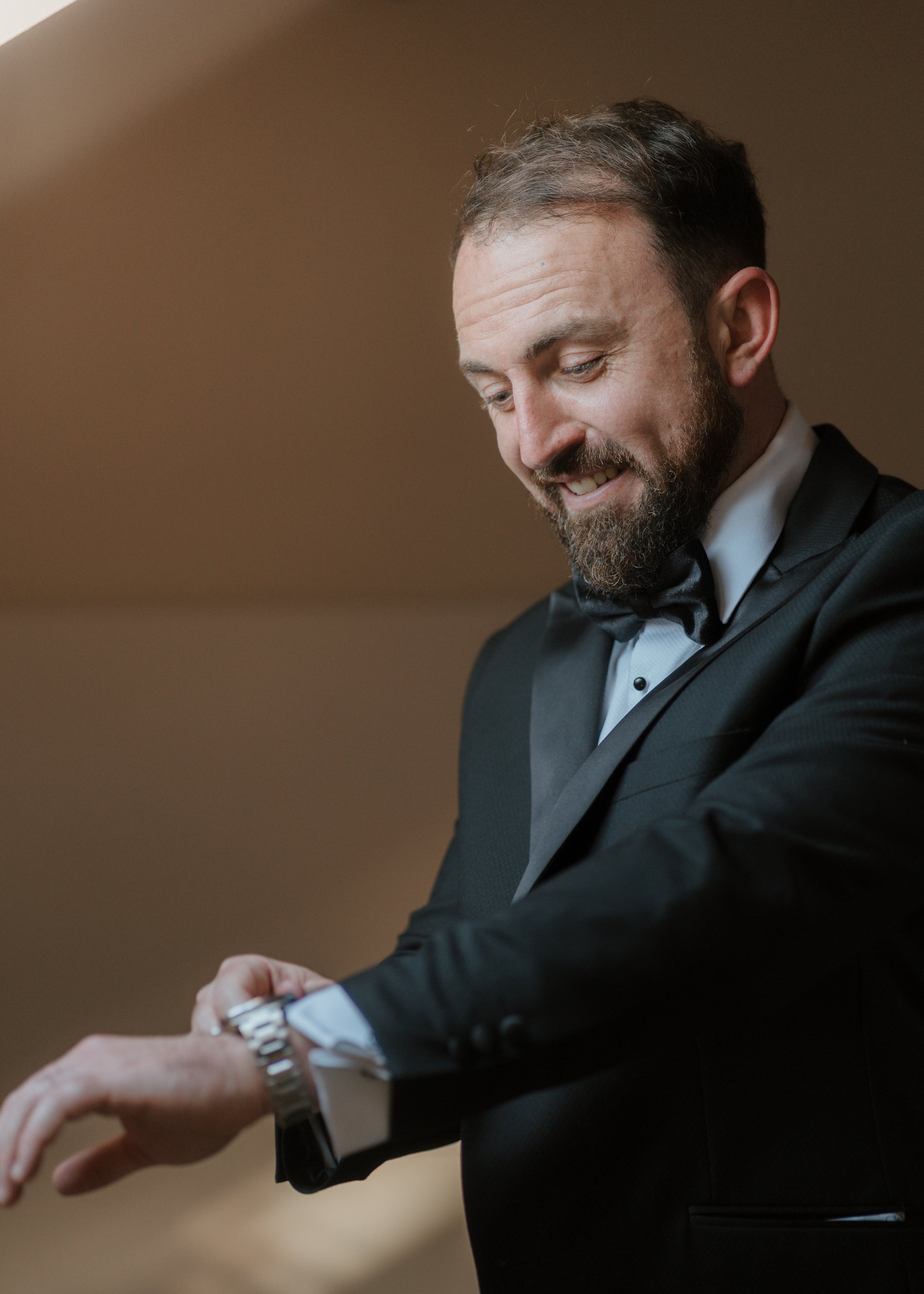 groom adjusting his watch whilst getting ready for his wedding at gaynes park in essex