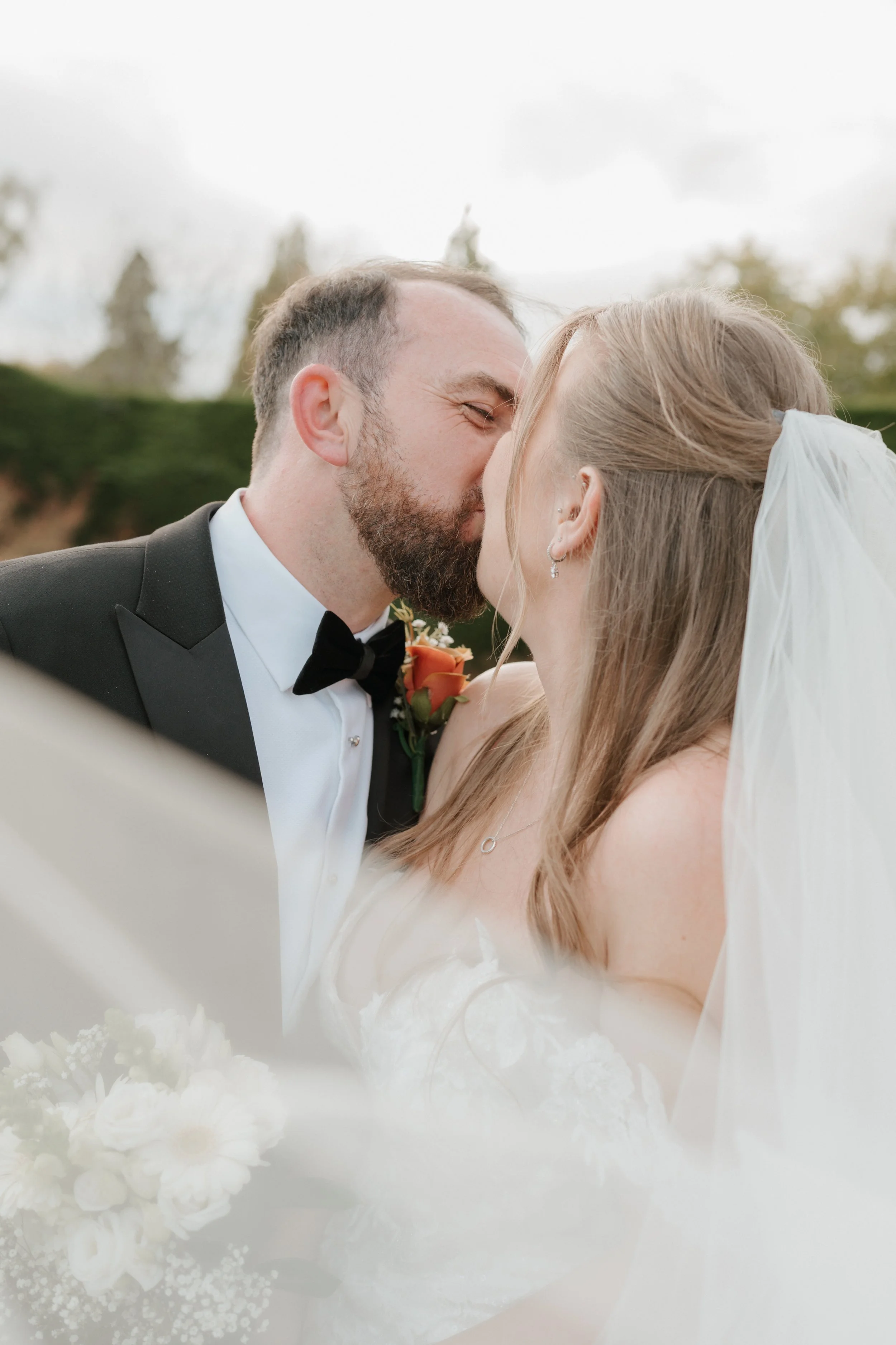 bride and groom kissing under a veil