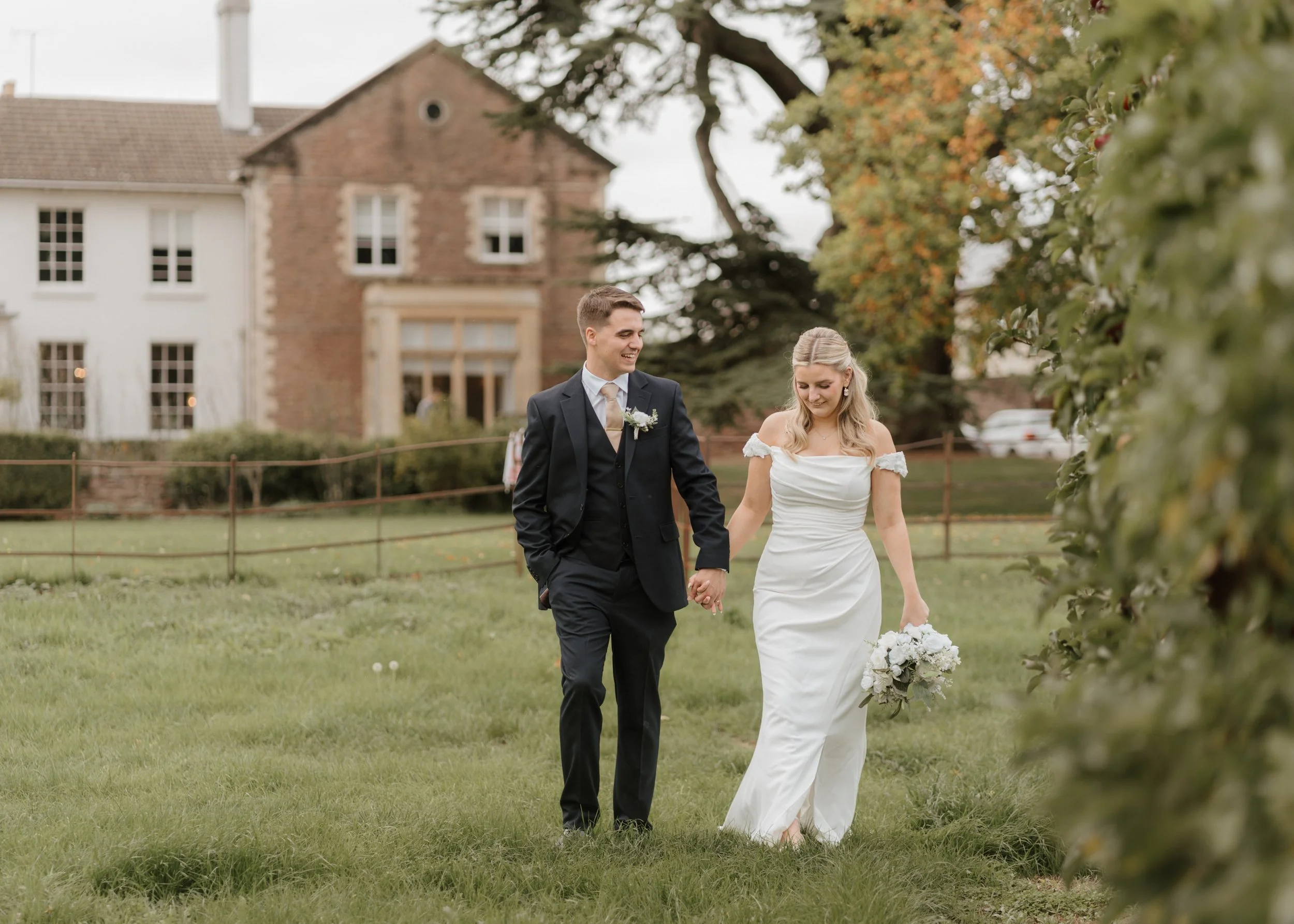 bride and groom walking through vineyard of glewstone court