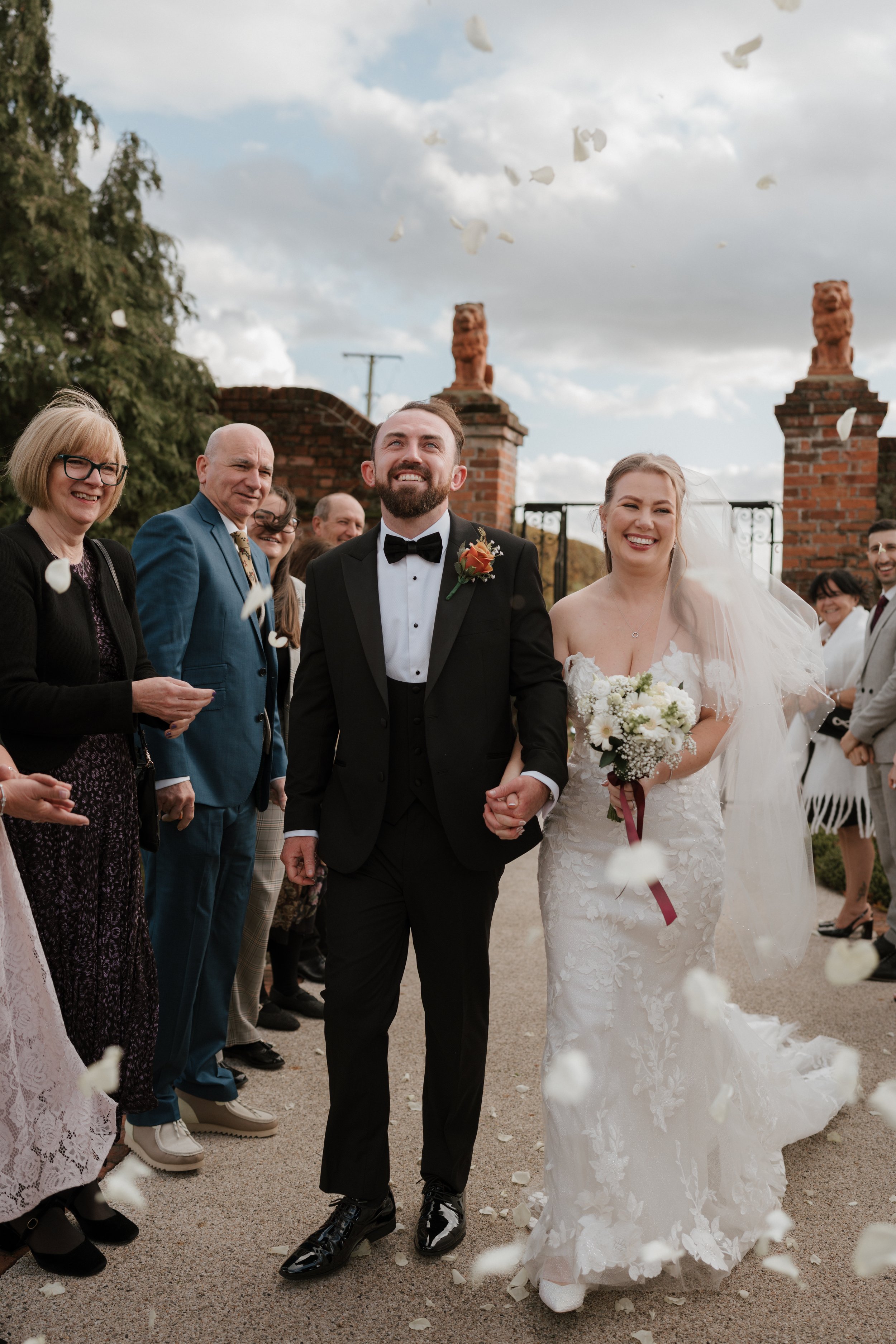 bride and groom walking through confetti tunnel at gaynes park wedding venue in essex