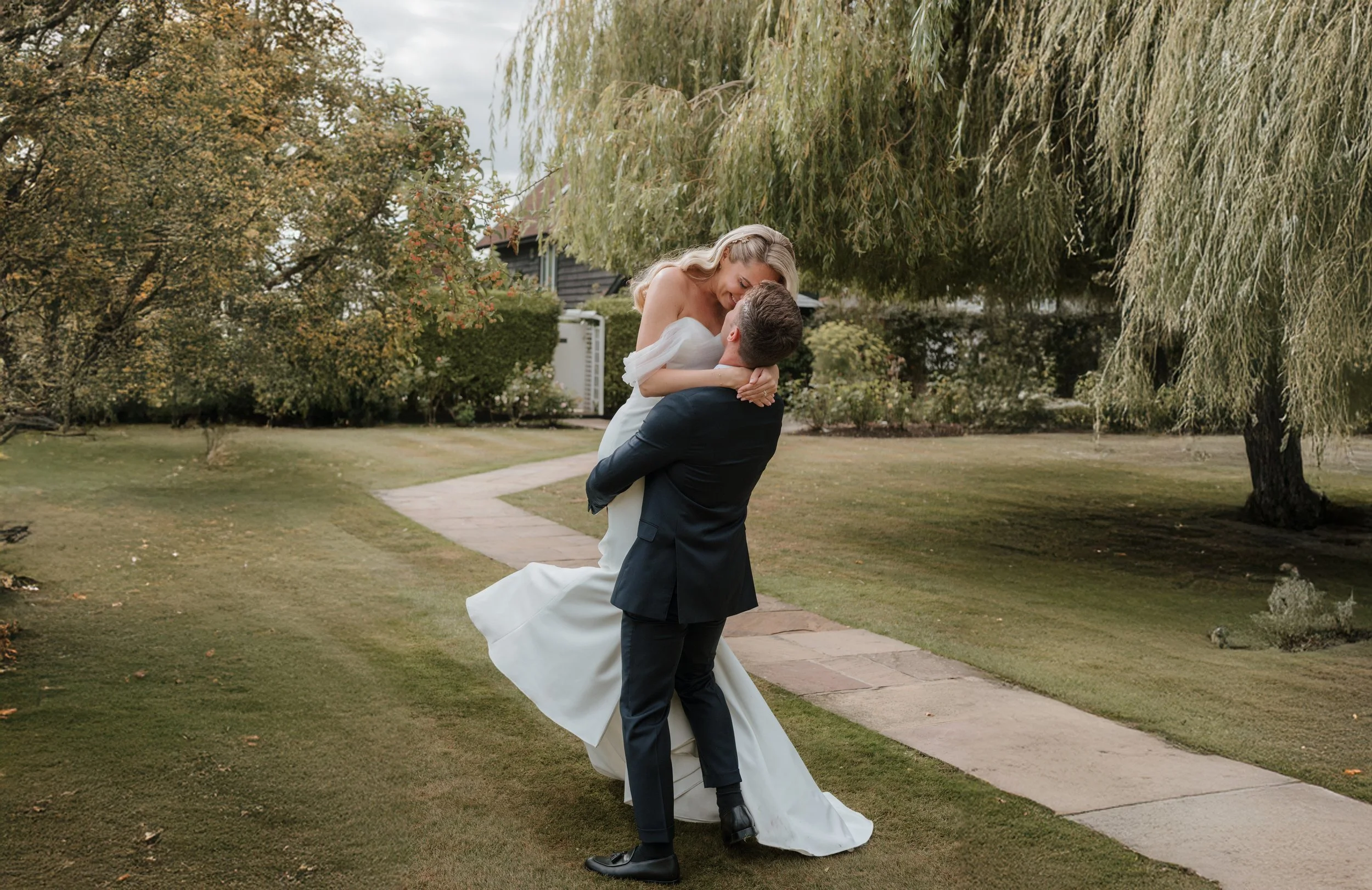 groom picking up his bride and spinning her around at sunset
