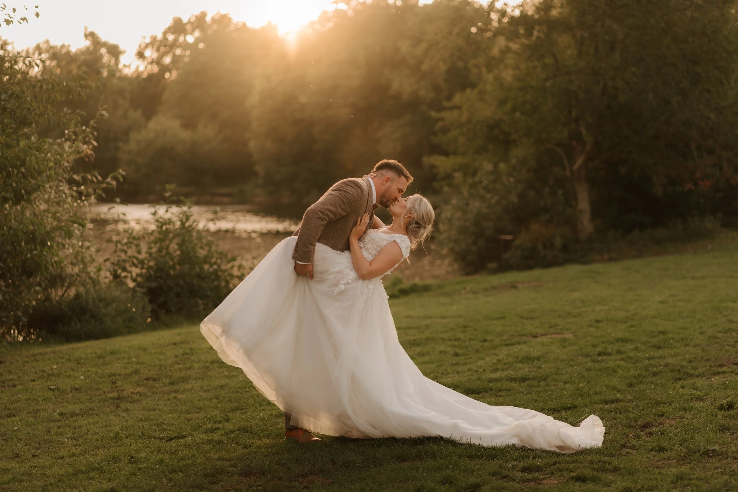 groom dipping bride at sunset by pond wedding