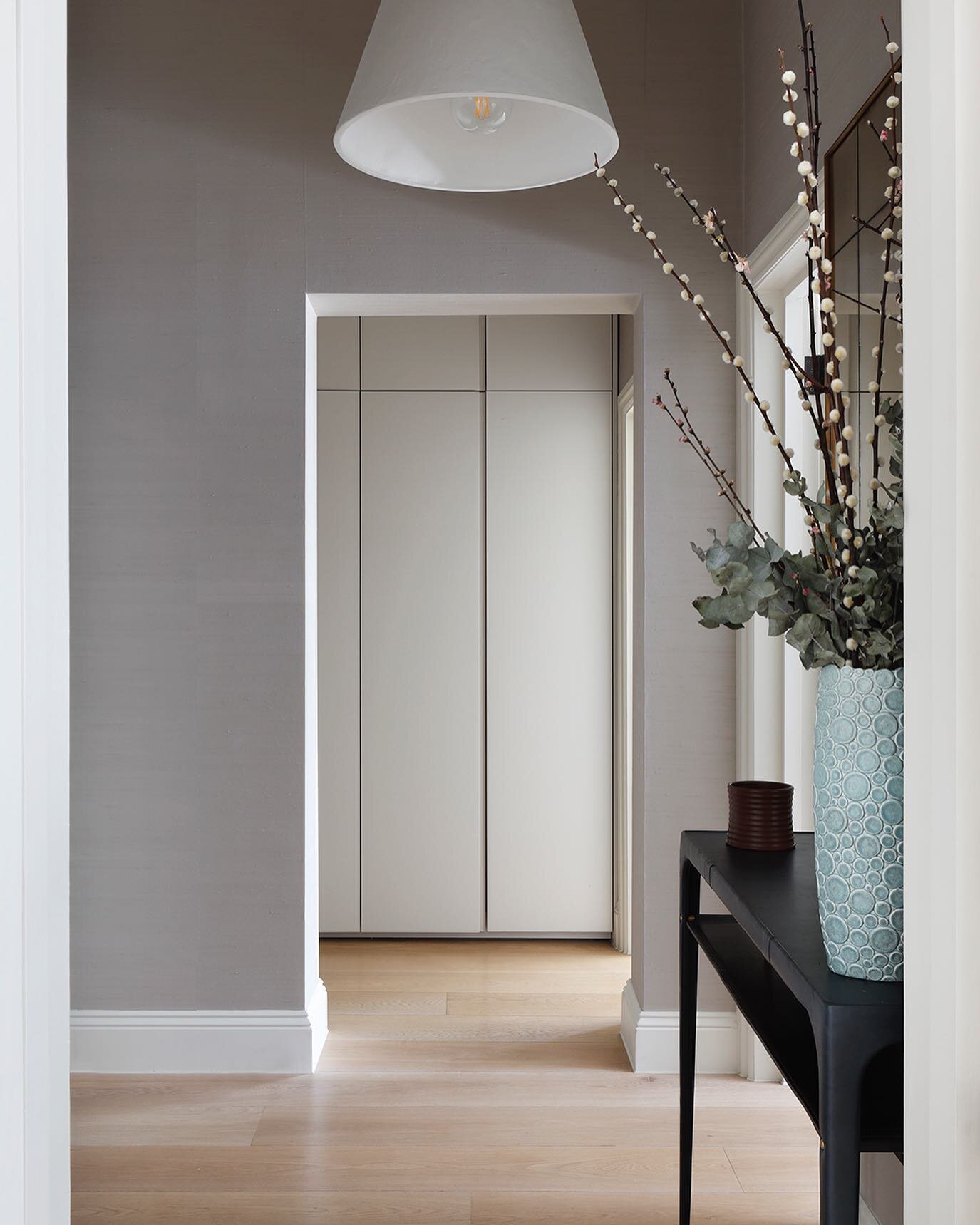 It may be small, but this entrance hall packs a punch. The silk wall covering adds warmth and contrasts with the pale oak flooring. An over scaled plaster pendant light, leather console table and antique mirror are the focal points upon entering the 