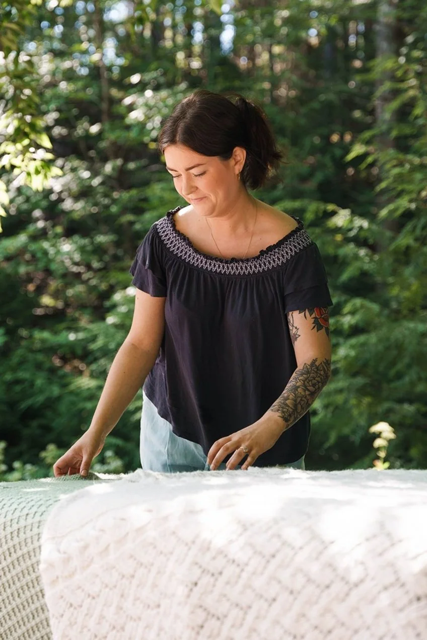 Woman arranging a blanket outdoors in a forest setting.