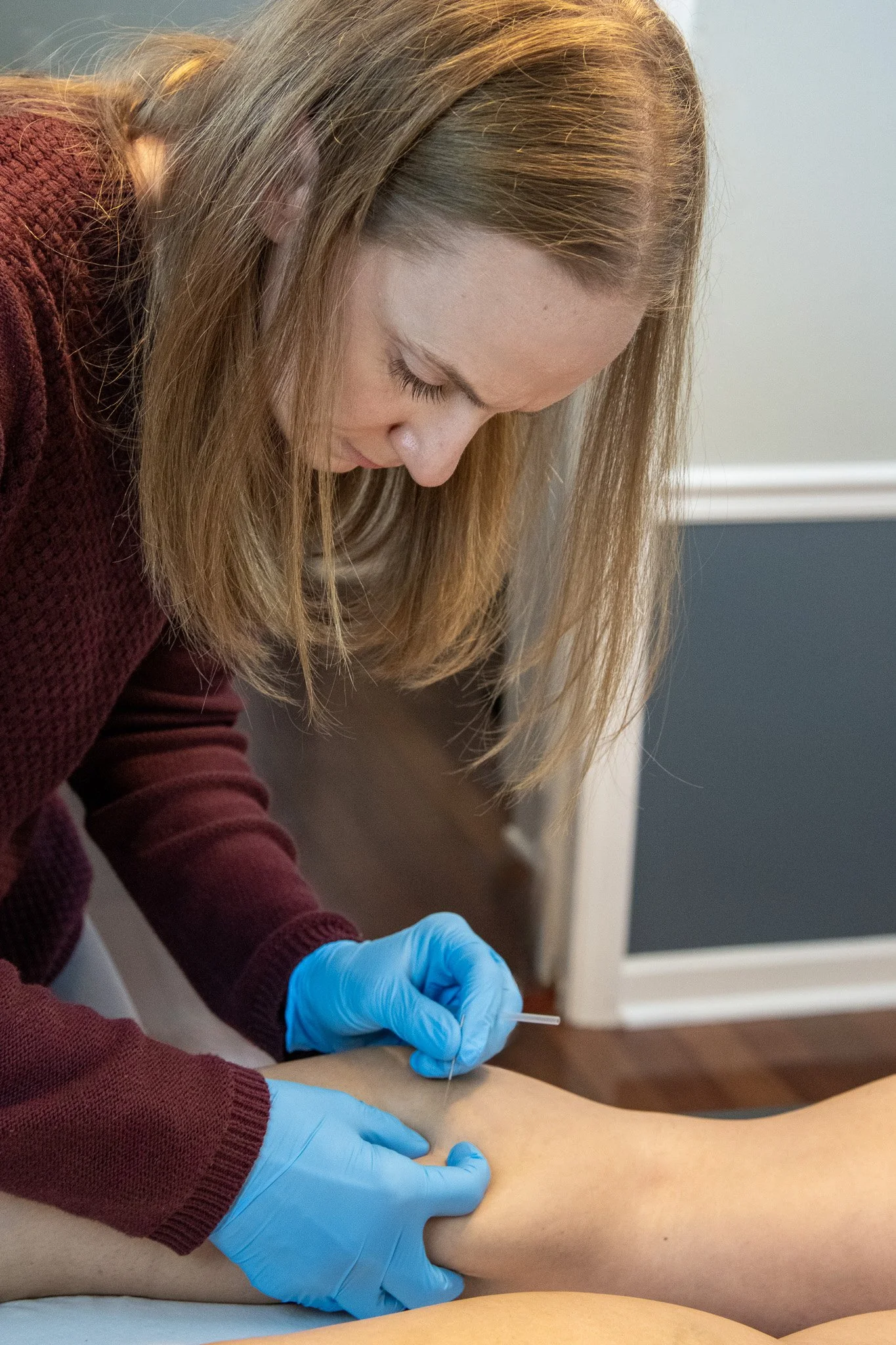 Lauren demonstrating dry needling on a patient's calf muscle.