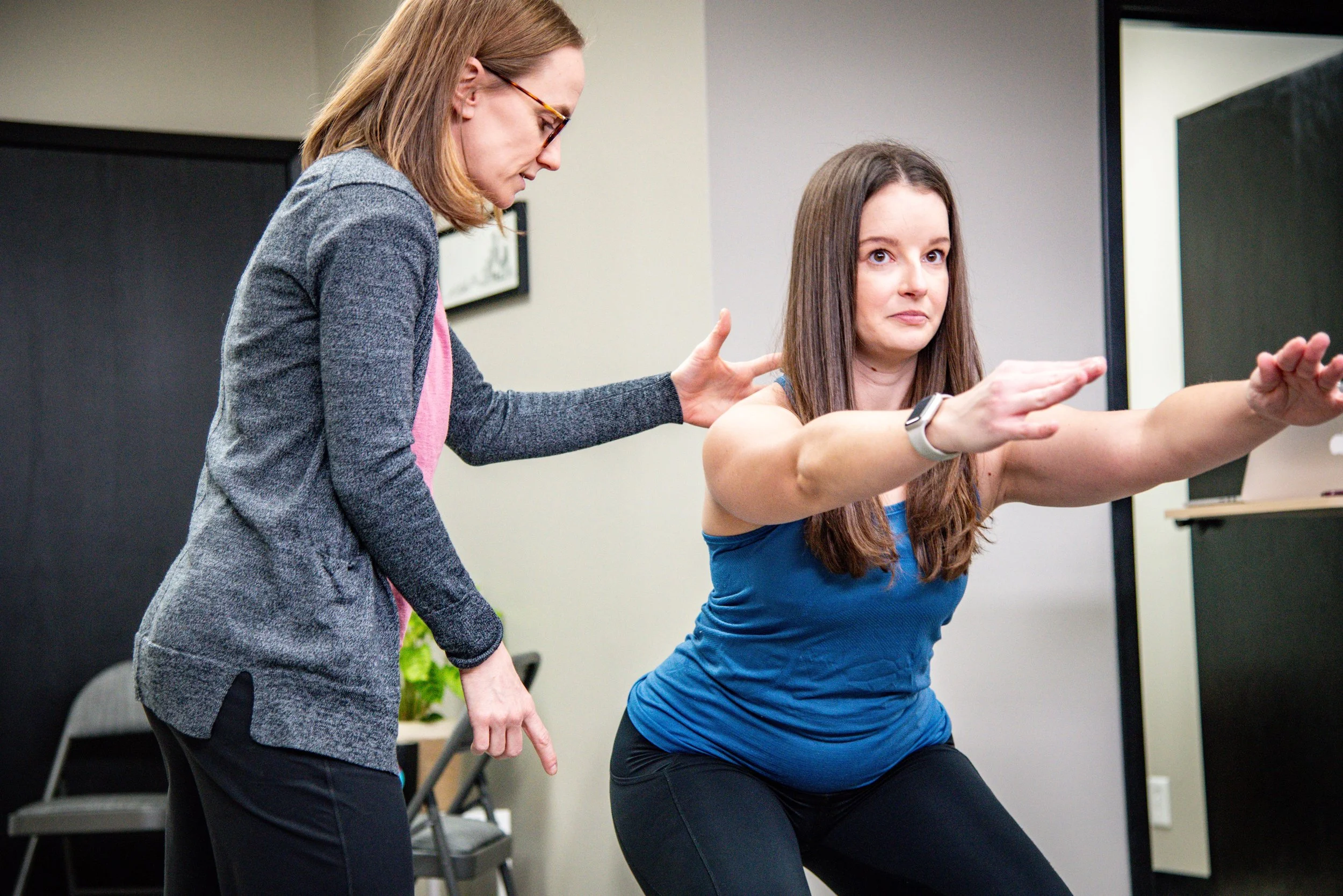 Lauren Hogan, PT working with a patient on proper body mechanics for squatting.