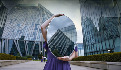 View of woman holding a mirror in front of face