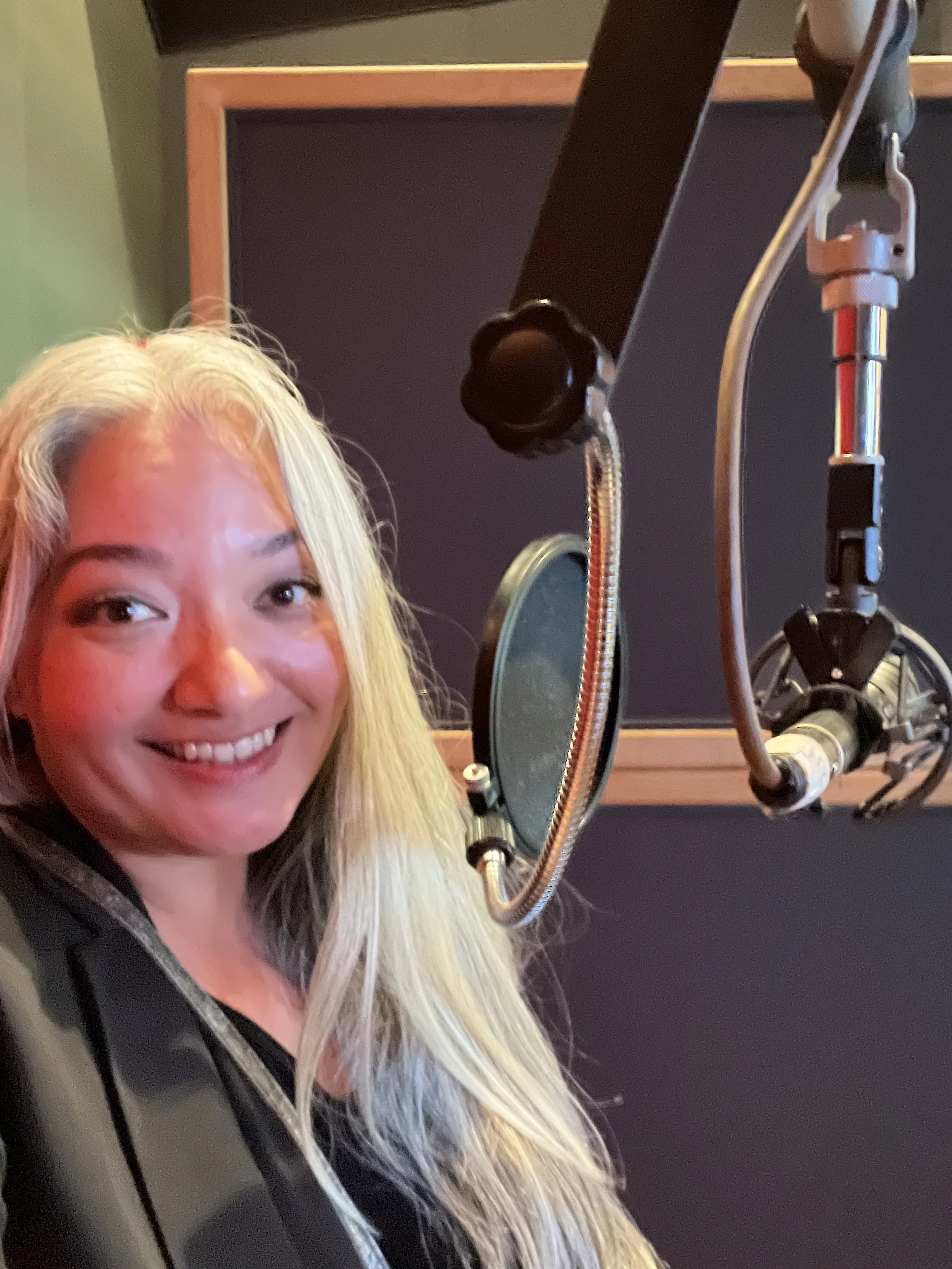 Hawaii SAG-AFTRA voiceover actor. A woman with long silver hair smiling at a microphone in a recording studio.