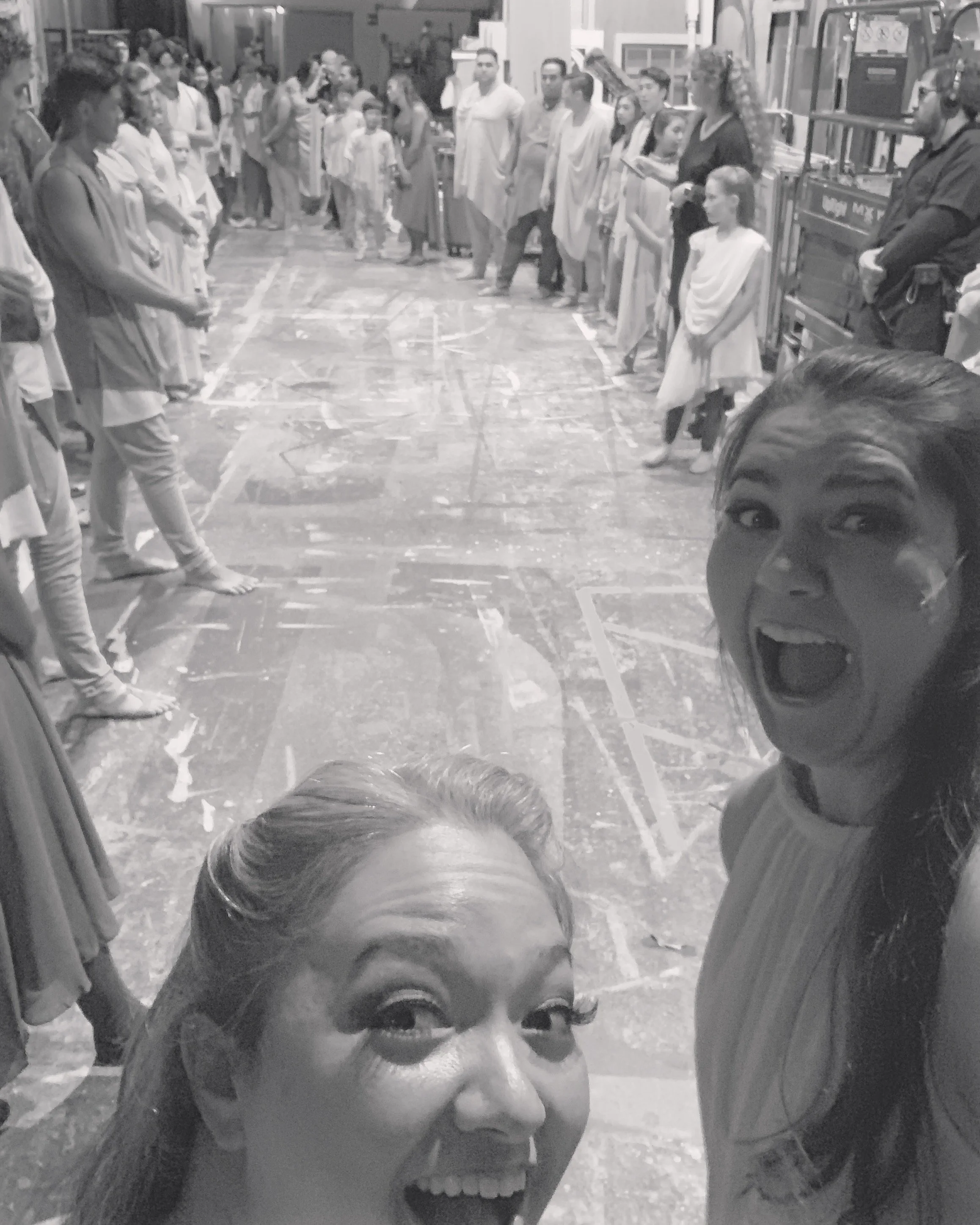 CHILDREN OF EDEN a Broadway musical by I'm A Bright Kid Foundation at Paliku Theatre. Two women taking a selfie in front of a line of performers dressed in costumes, with some children and spectators in the background.