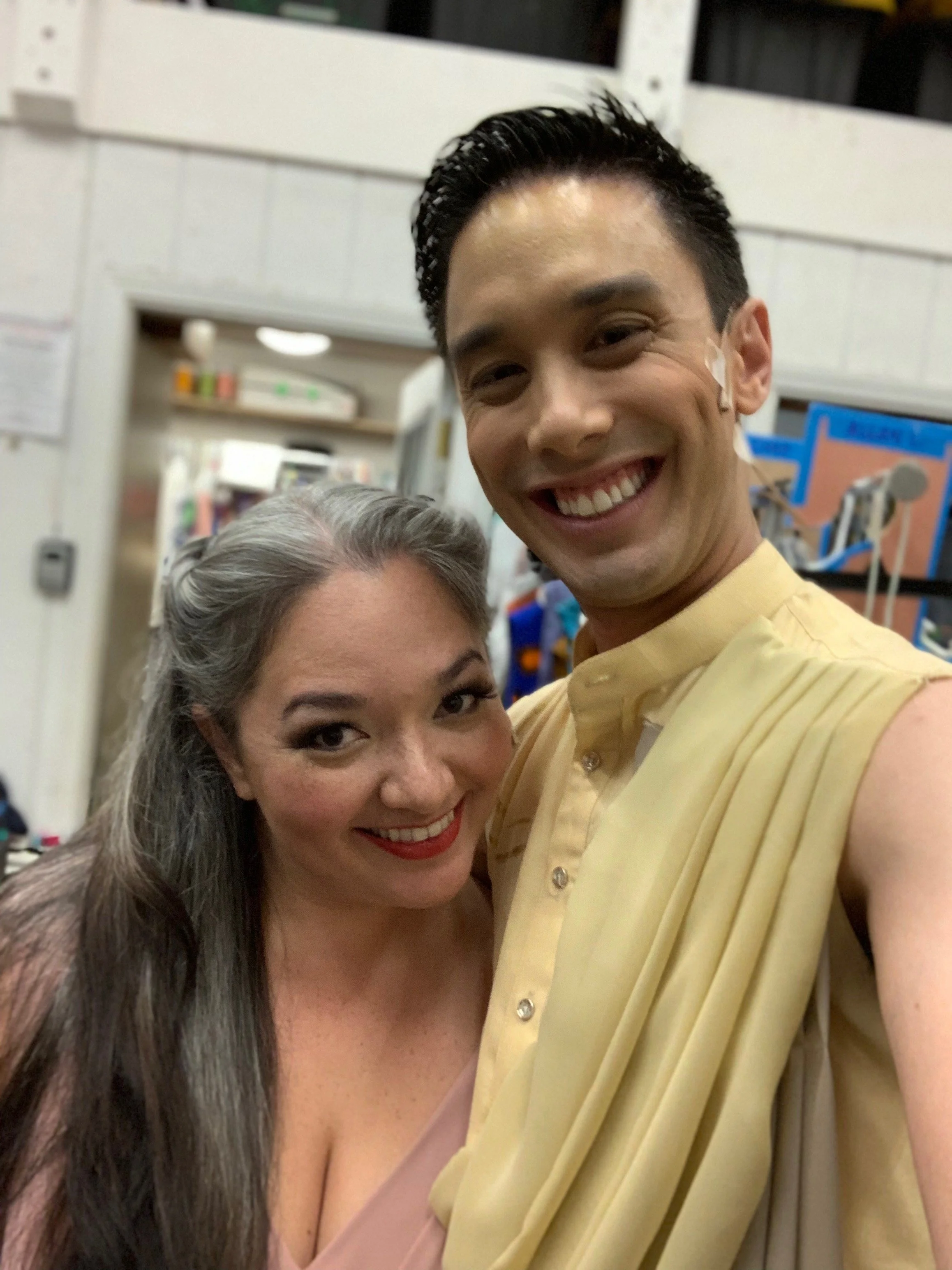 CHILDREN OF EDEN a Broadway musical by I'm A Bright Kid Foundation at Paliku Theatre. A smiling man and woman taking a selfie together in a room with medical equipment in the background.