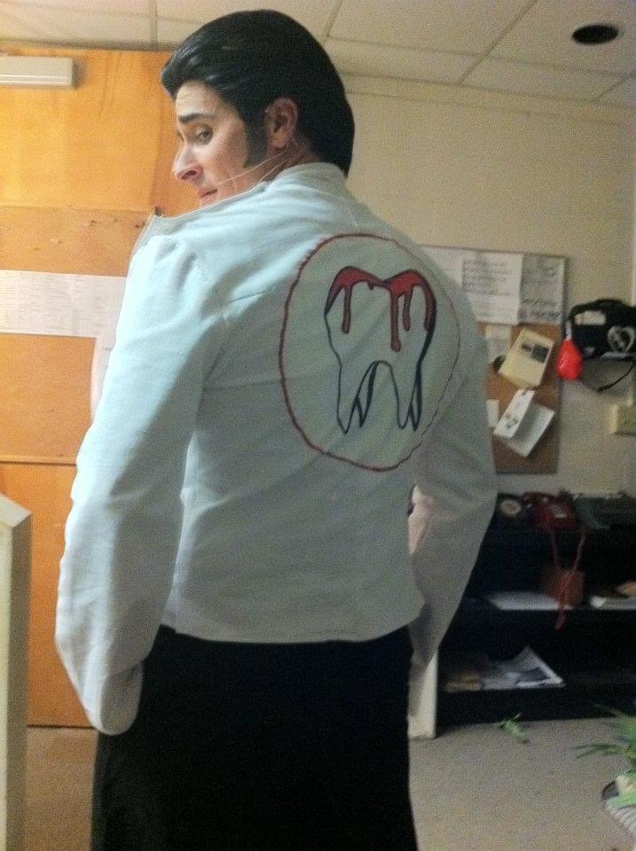 LITTLE SHOP OF HORRORS a comedic musical at Manoa Valley Theatre in Honolulu, Hawaii. The Dentist. Man wearing a white jacket with a red and black drawing of a bleeding tooth on the back.