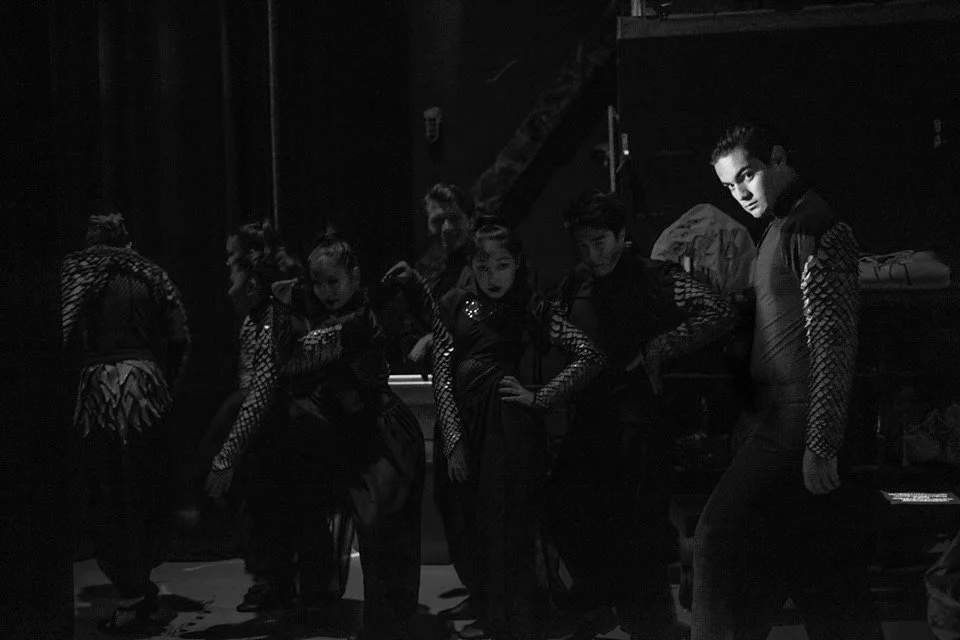 CHILDREN OF EDEN a Broadway musical by I'm A Bright Kid Foundation at Paliku Theatre. Group of young performers in costumes backstage, posing for a photo in a dimly lit area.