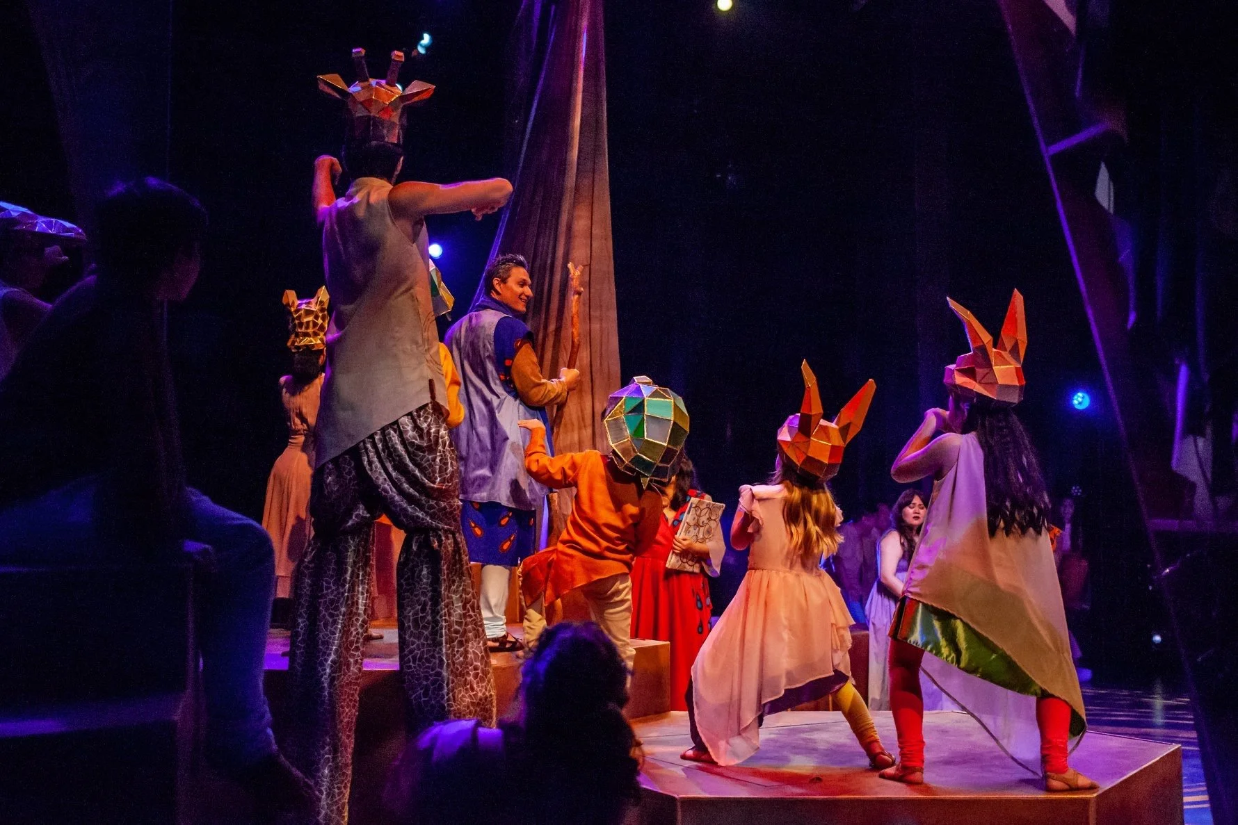 CHILDREN OF EDEN a Broadway musical by I'm A Bright Kid Foundation at Paliku Theatre. Children in costumes with animal and geometric headpieces performing on stage in a theatrical production.