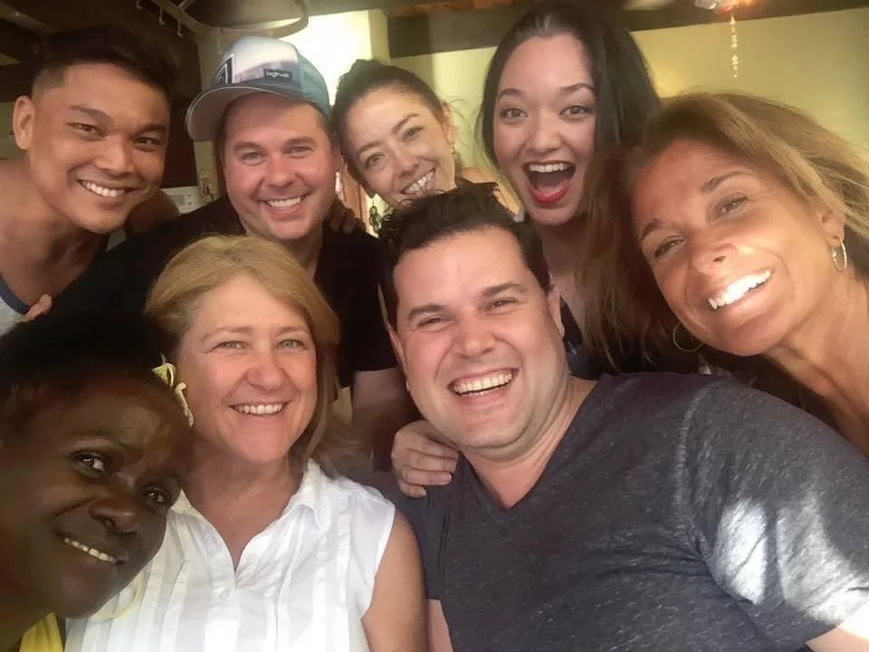 RISE UP: A BENEFIT CONCERT BY MELINA LILLIOS at Paliku Theatre in Kaneohe, Hawaii. Group of nine diverse people smiling and taking a selfie together indoors.